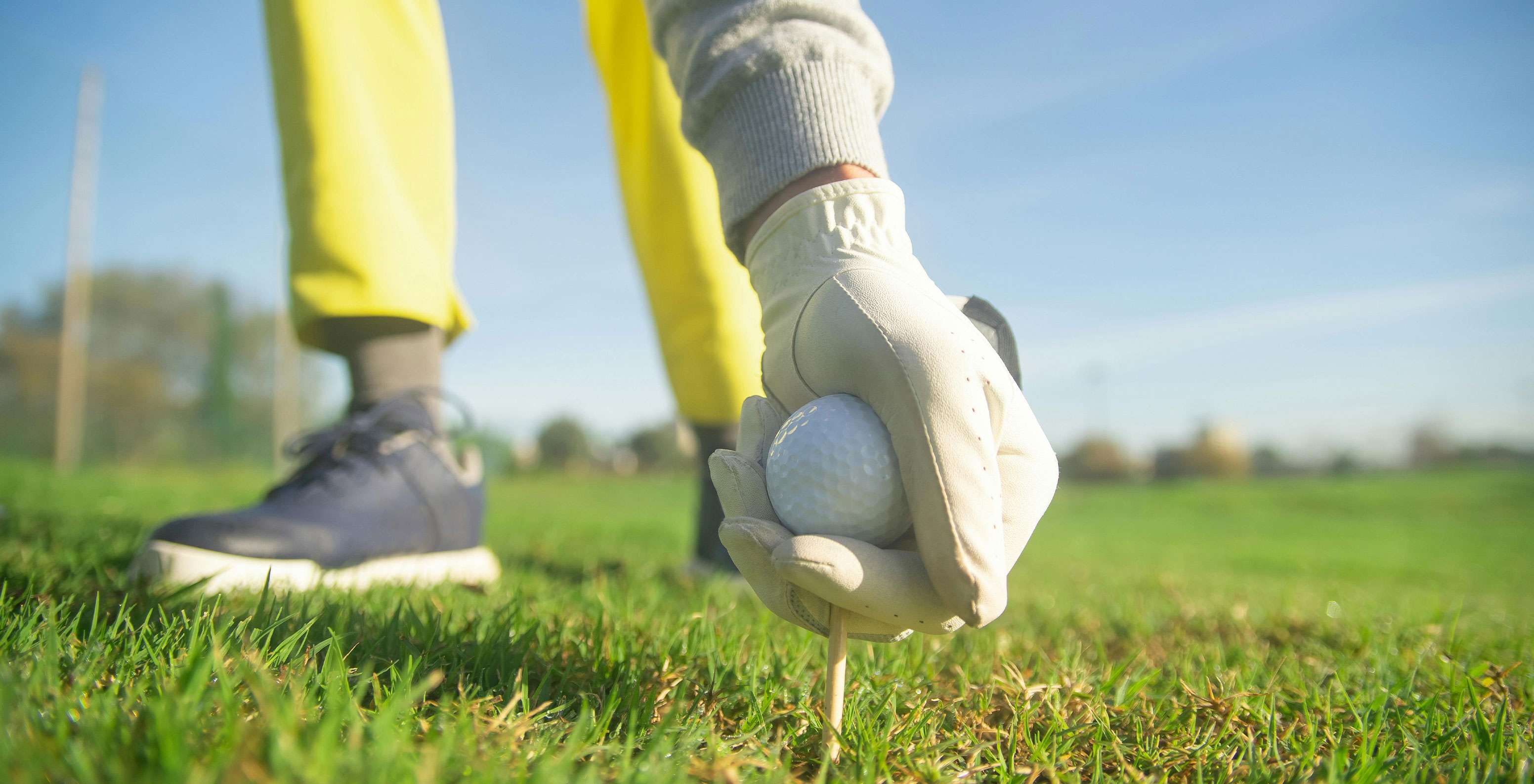 Persona agachándose para recoger la bola de golf en el campo y preparándose para el siguiente golpe