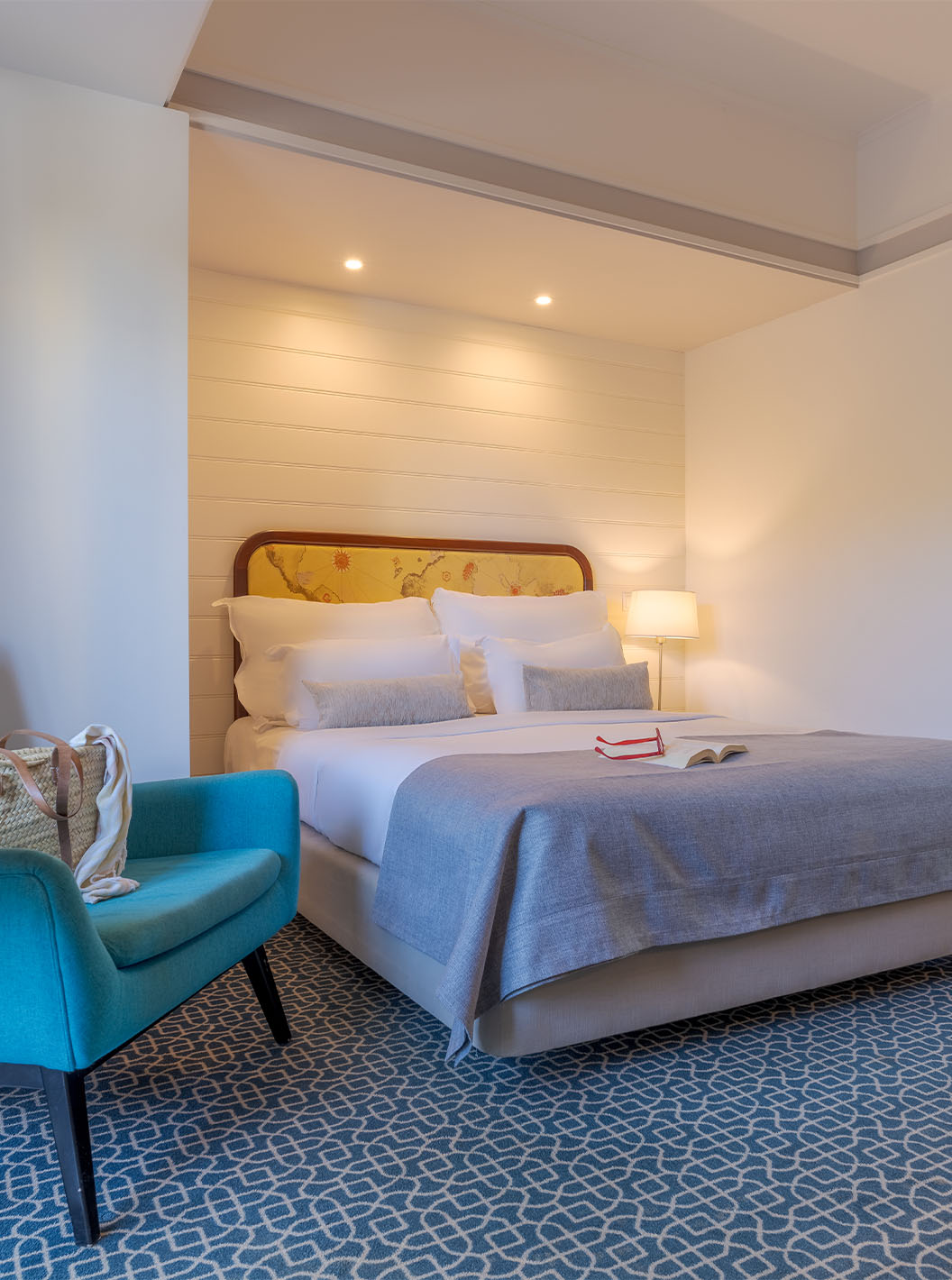 El Deluxe del Pestana Alvor Praia tiene cama matrimonial, mesa con sillón azul, espejo y alfombra geométrica