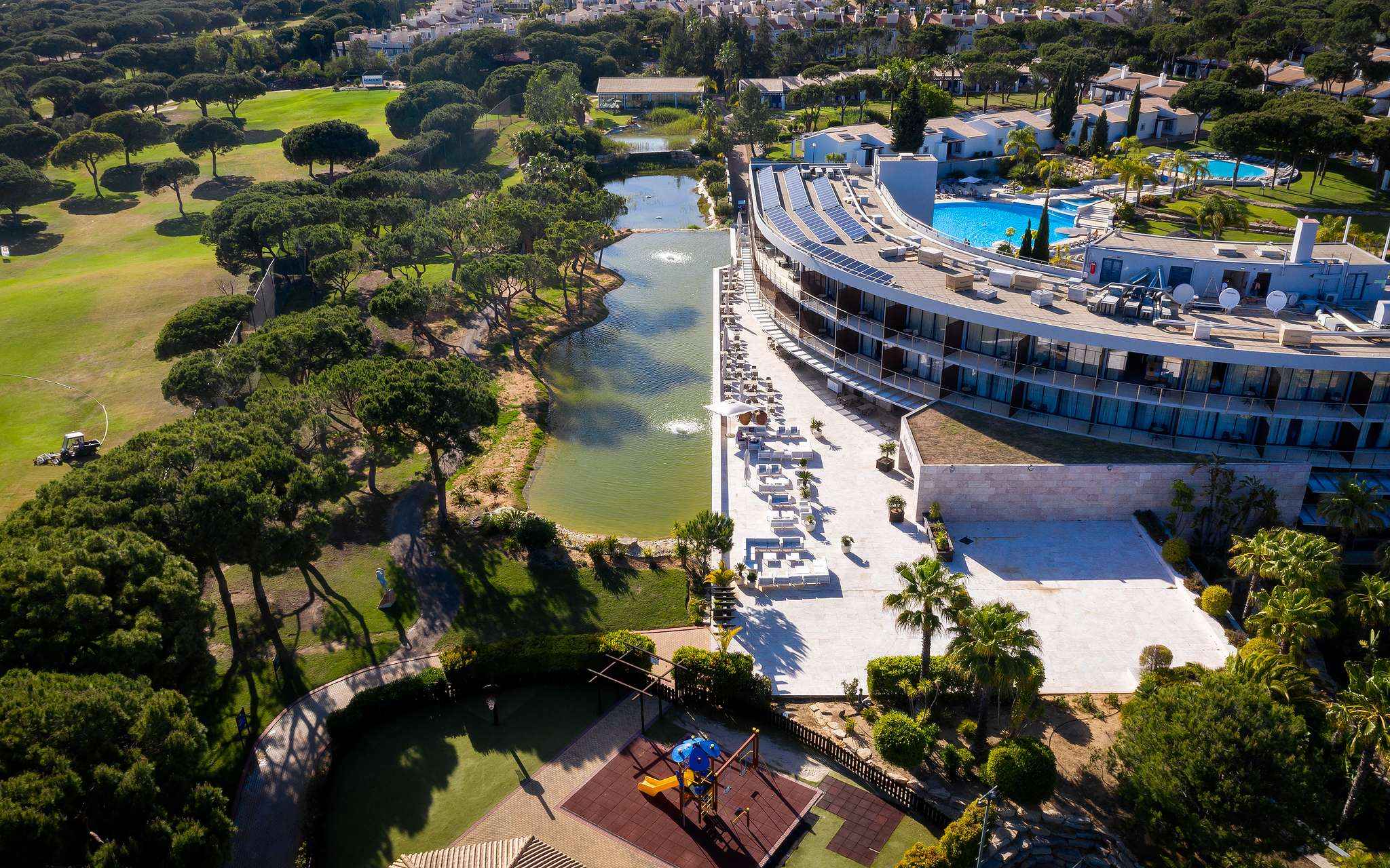 Vista de Pestana Vila Sol - Vilamoura, un hotel de 5 estrellas en Vilamoura con piscina, rodeado de un lago y vegetación