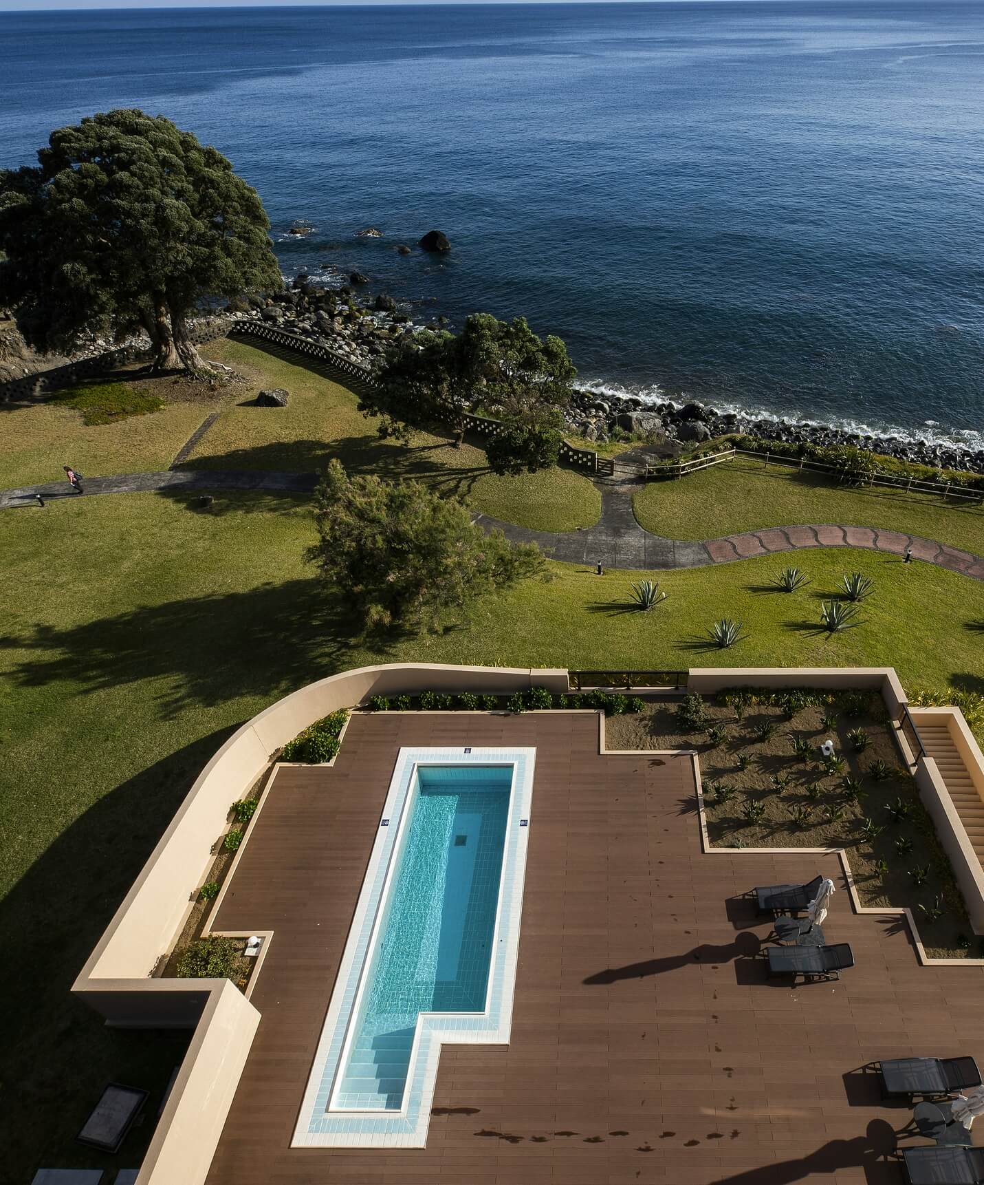 Piscina del Pestana Bahia Praia sobre tarima de madera con vistas al mar y zona verde alrededor
