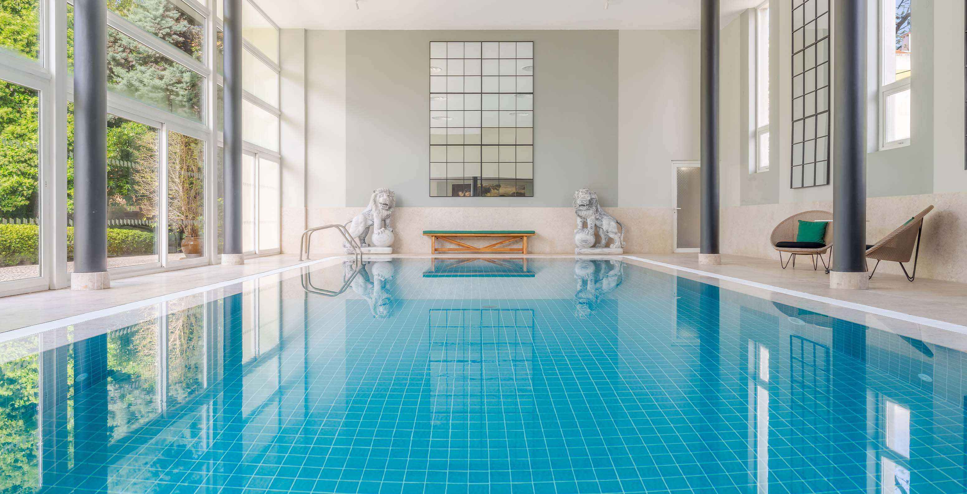 Piscina interior del Palace Lisboa Hotel en un Palacio en Lisboa con Spa con luz natural y dos esculturas de leones