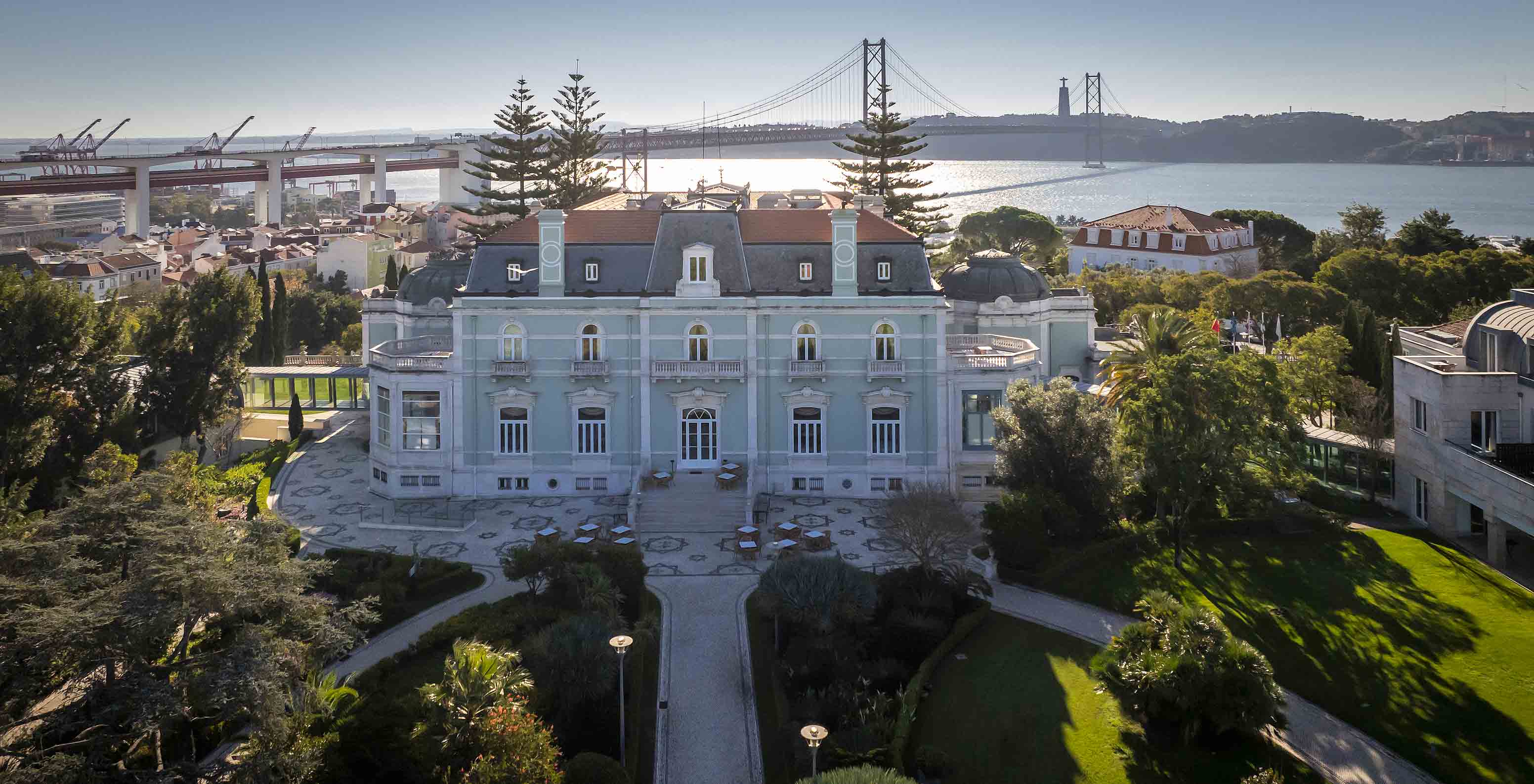 Vista aérea del edificio principal del Pestana Palace Lisboa con el puente 25 de Abril, el río Tajo y el Cristo Rey al fondo