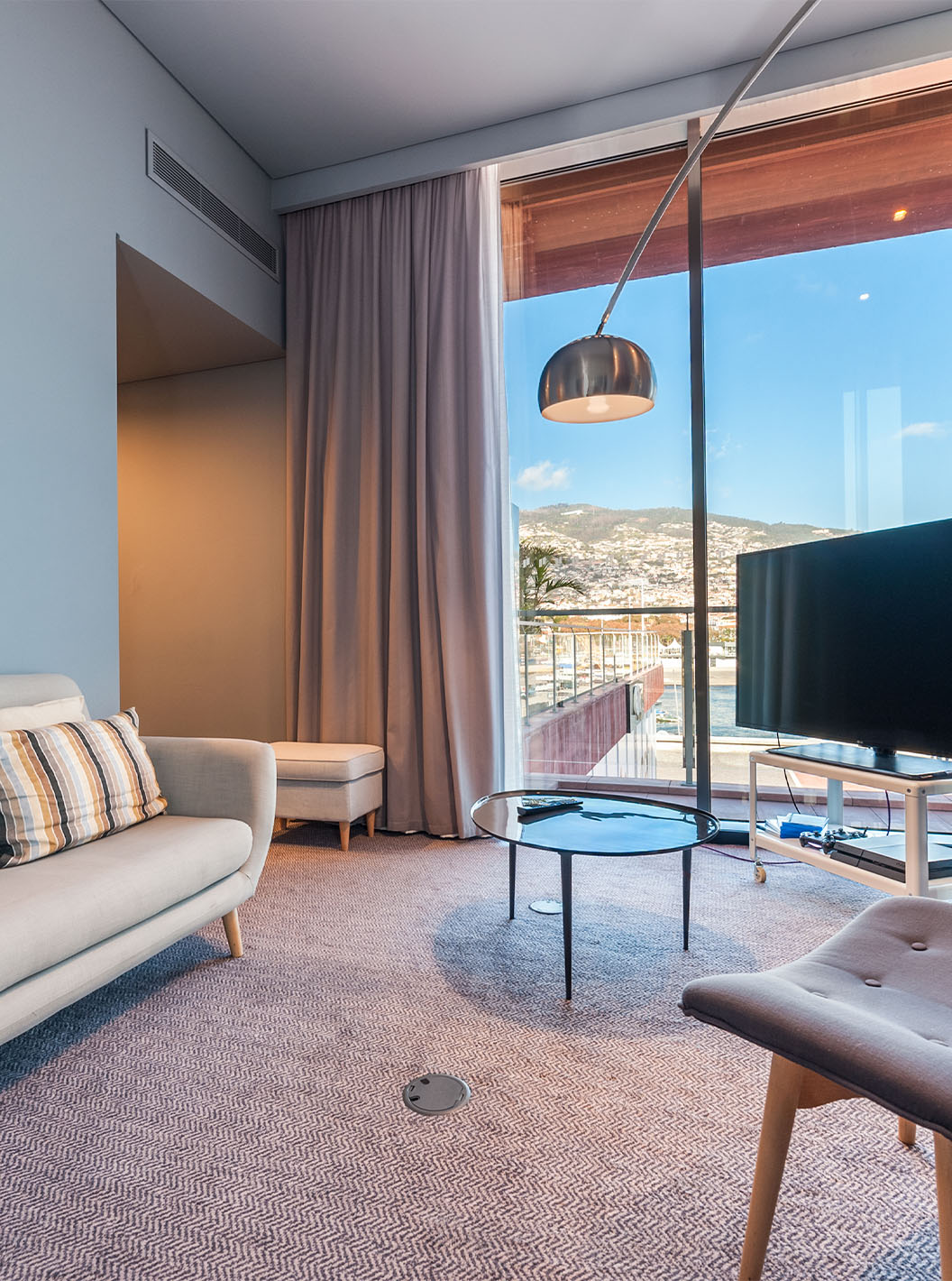 La Suite CR7 del Pestana CR7 Funchal tiene una sala de estar con un sofá, una televisión y una ventana con vista a Funchal