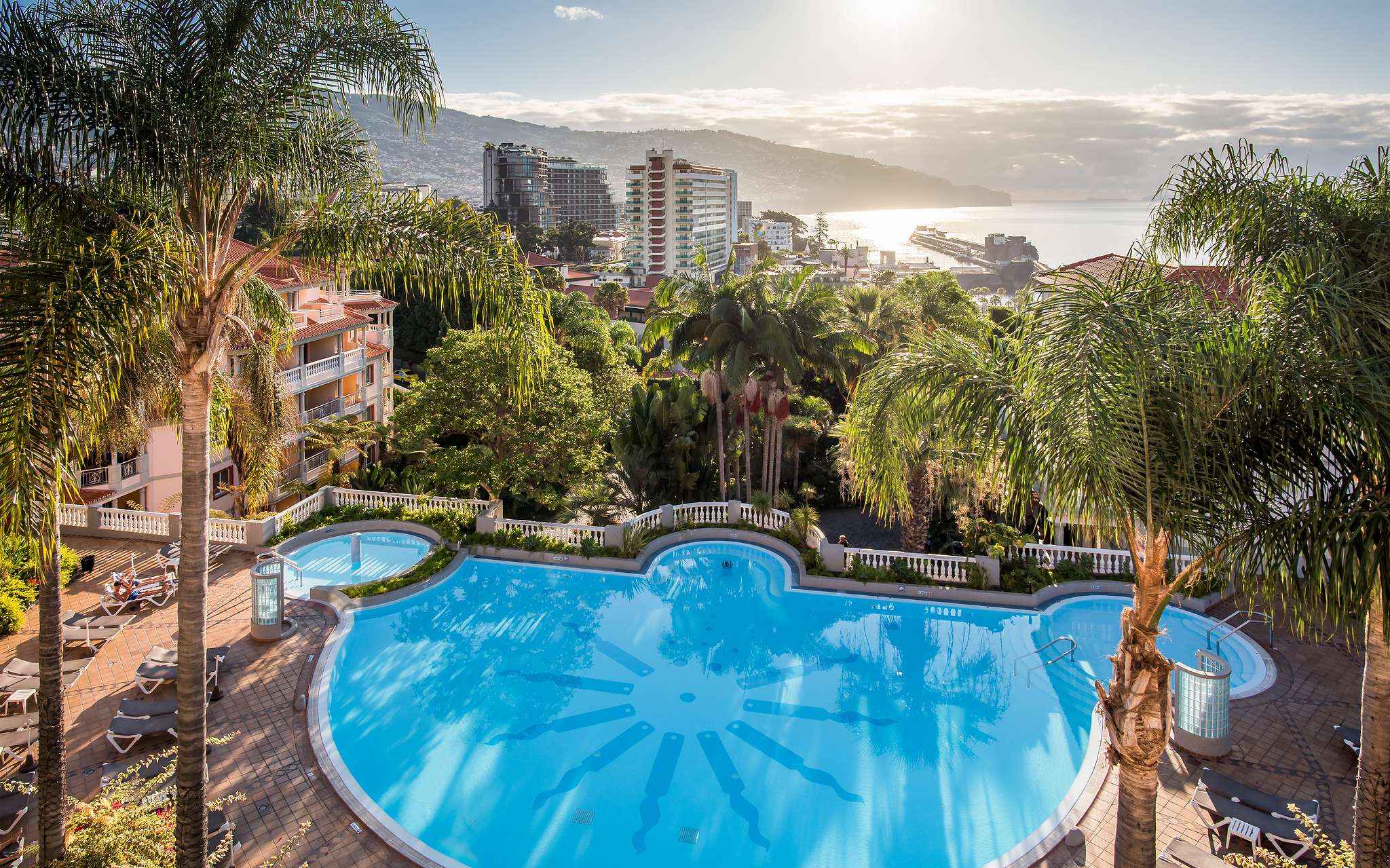 Vista aérea de la piscina de Pestana Miramar, un hotel en Madeira cerca de la playa, rodeado de palmeras