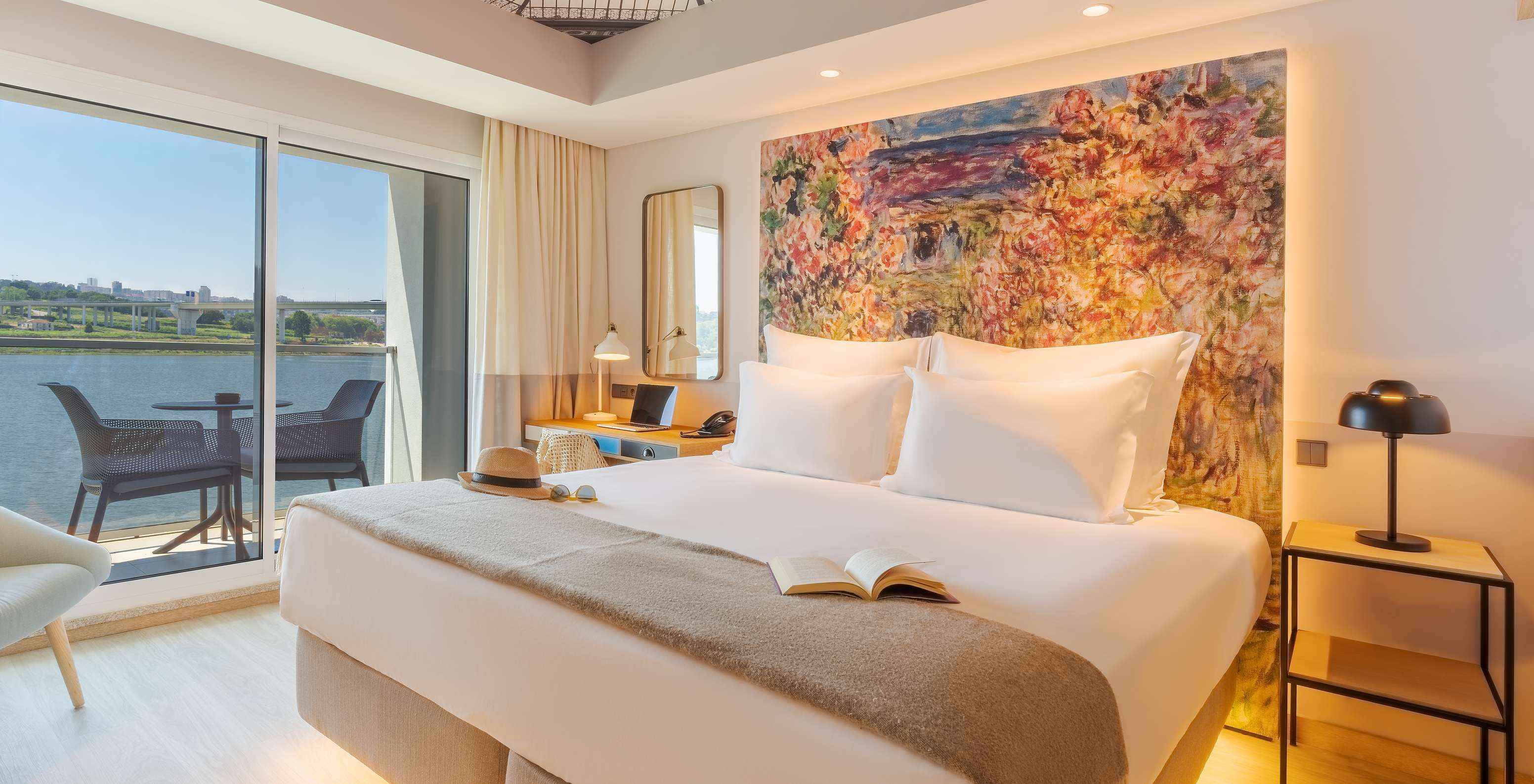 El cuarto Deluxe River View del Pestana Douro Riverside cuenta con una cama de matrimonio, mesa de noche y terraza con vista