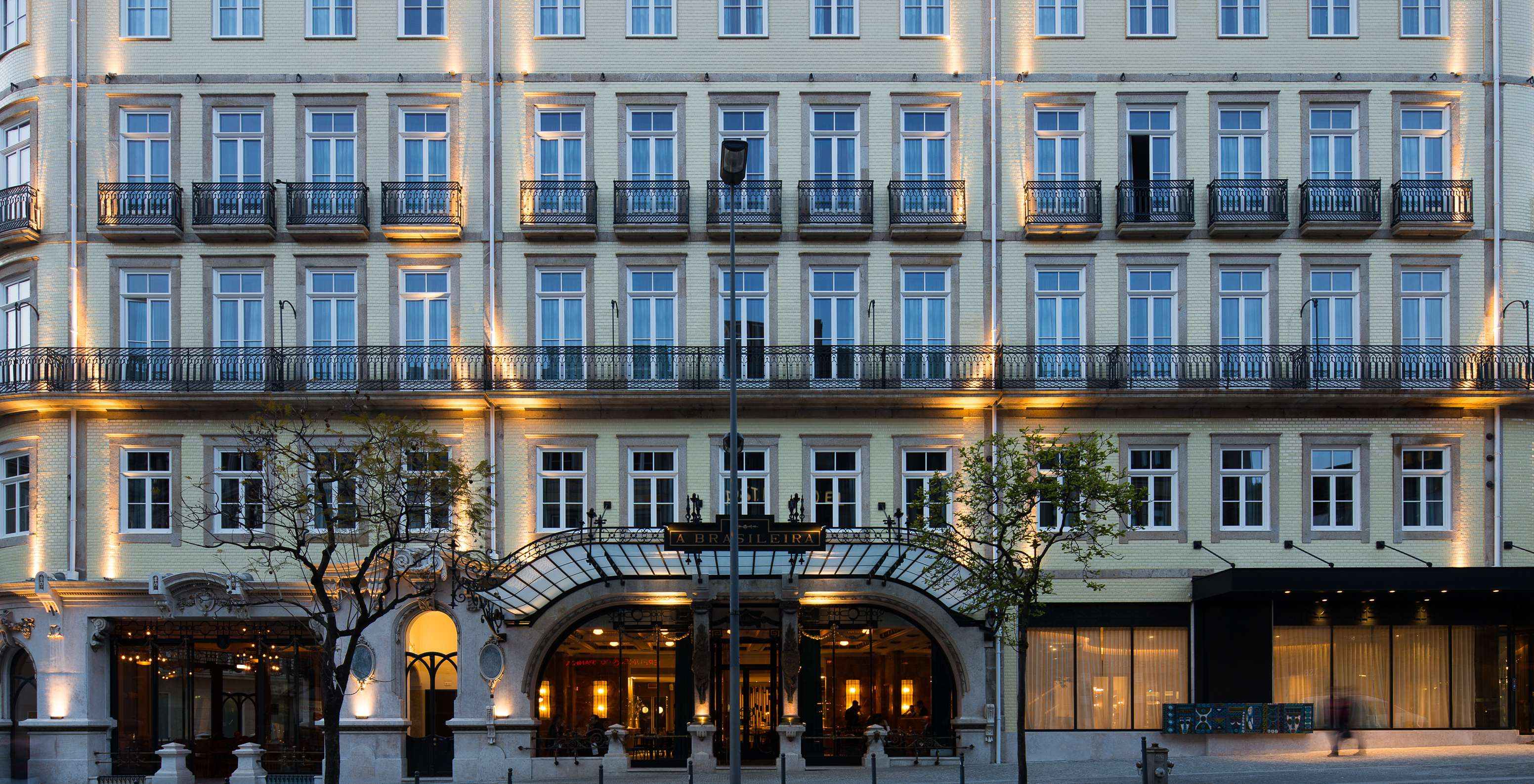 La fachada iluminada del hotel Pestana Porto - A Brasileira exhibe una arquitectura imponente con detalles clásicos