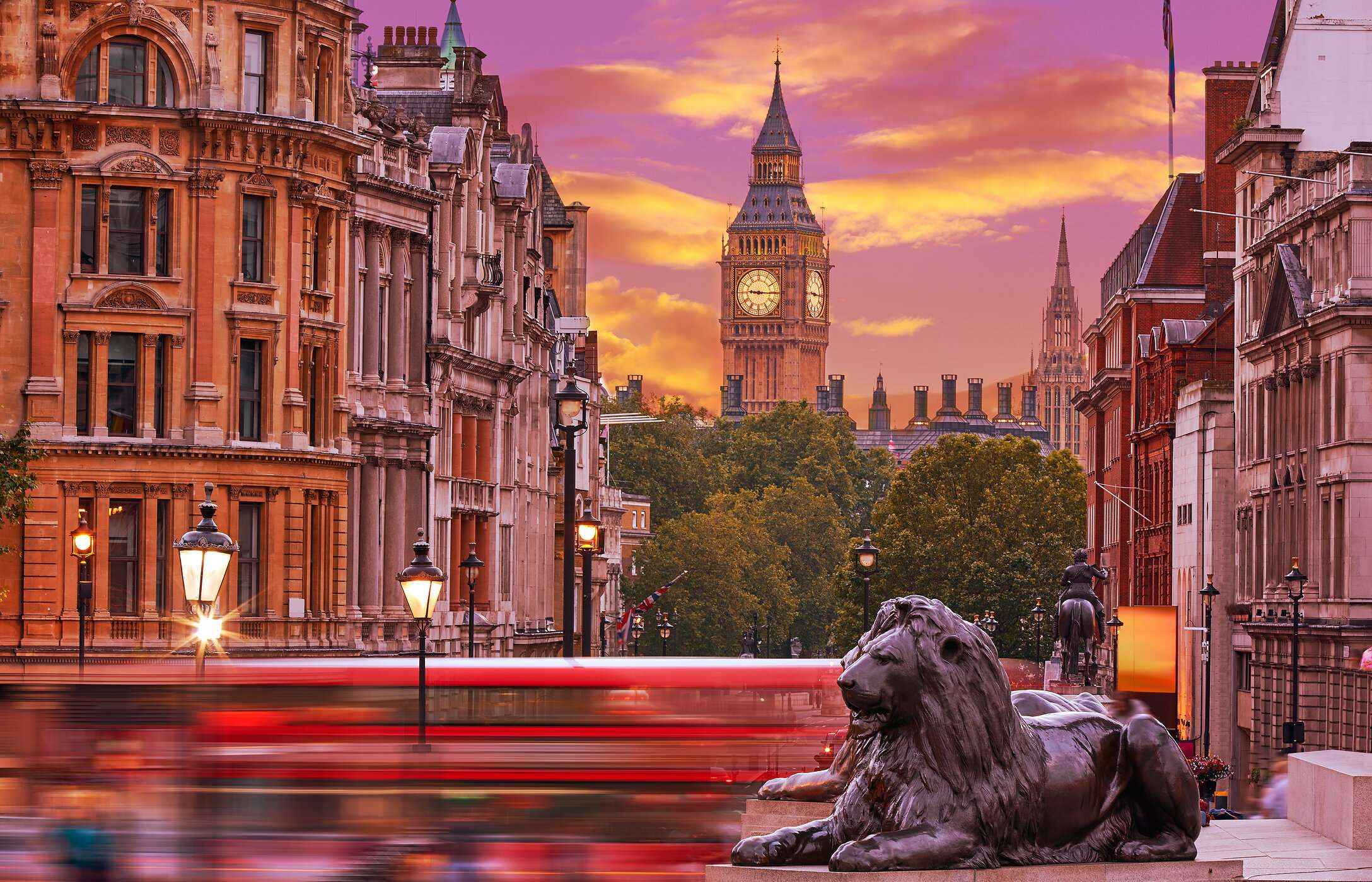 Agitación de autobuses en Trafalgar Square en Londres, con una estatua de un león en primer plano y el Big Ben al fondo.