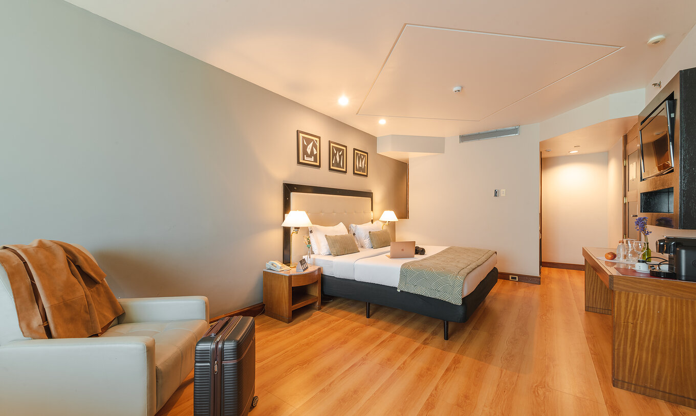 De Executive Suite van Pestana São Paulo heeft een kamer met een tweepersoonsbed, fauteuil en een koffer