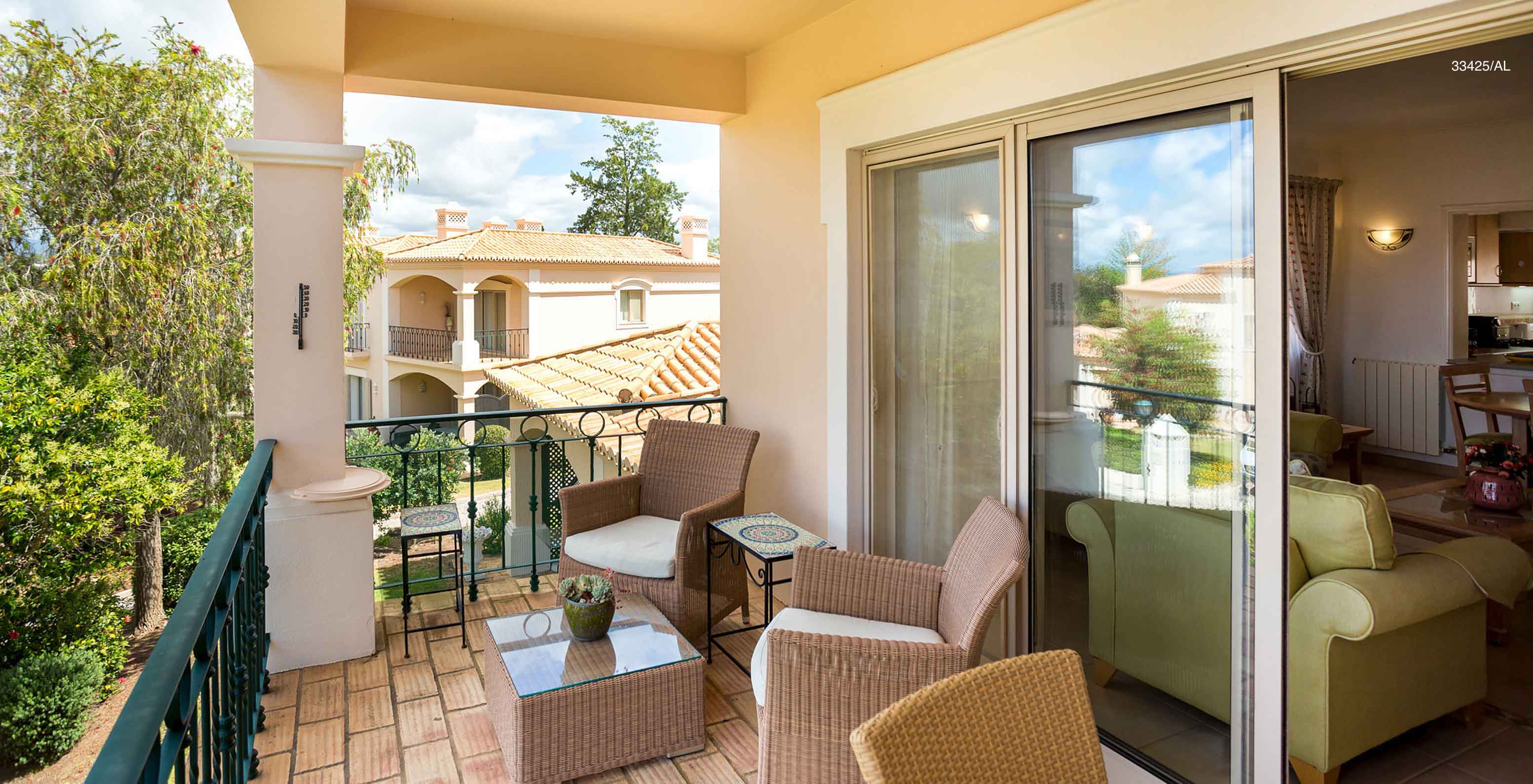 Het appartement Pestana Carvoeiro Golf T2 Standard heeft een balkon met een tafel, twee stoelen en uitzicht op de tuin