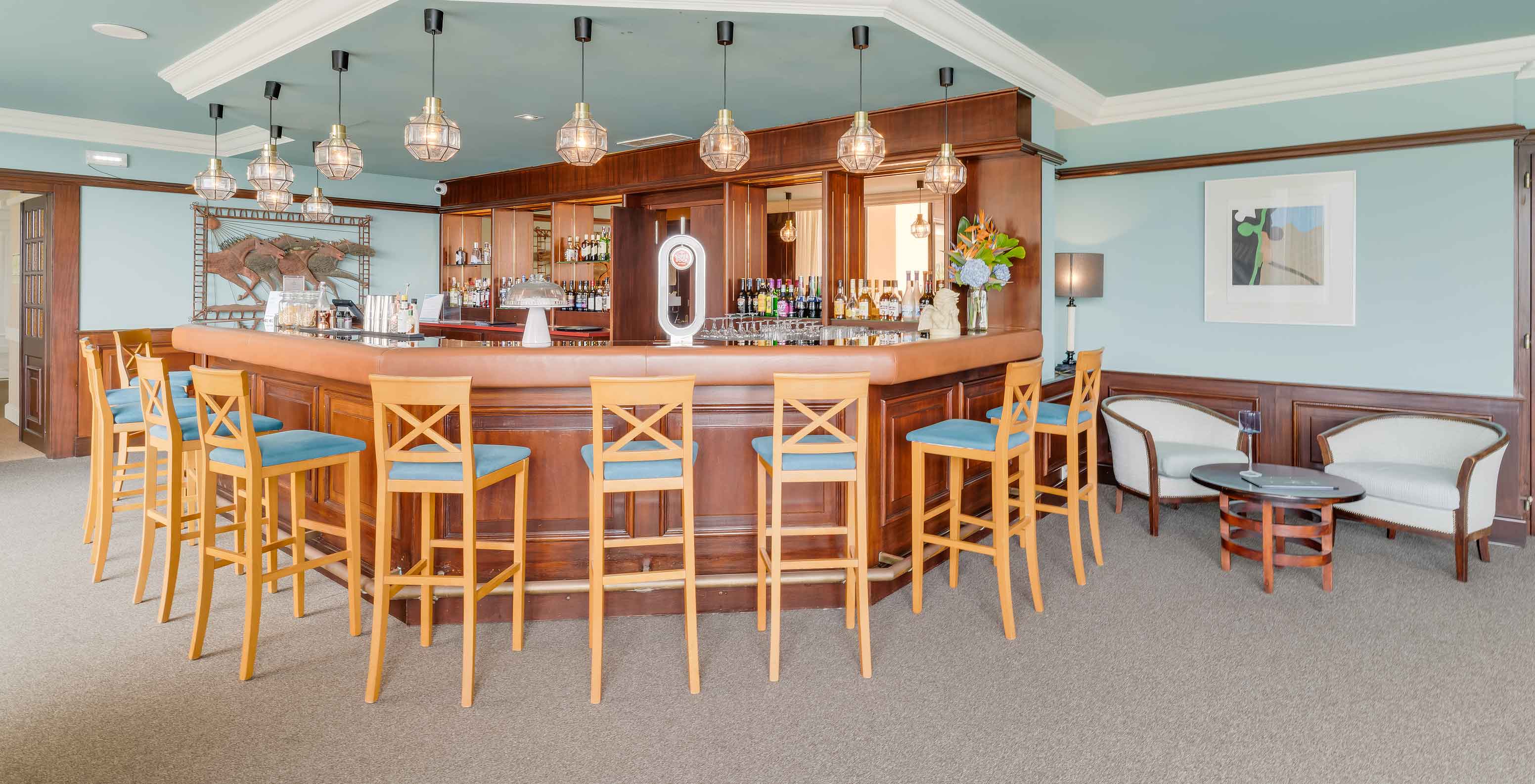 Bar in Pestana Bahia Praia met hoge stoelen, houten balie en moderne verlichting met hanglampen