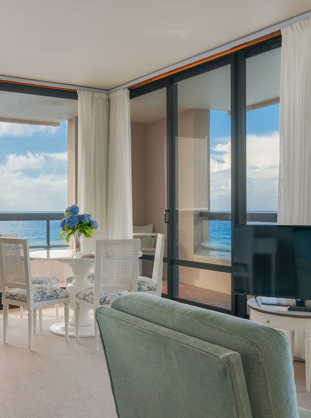 Suite van Pestana Bahia Praia heeft woonkamer met bureau, tafel en bank met televisie met uitzicht op zee