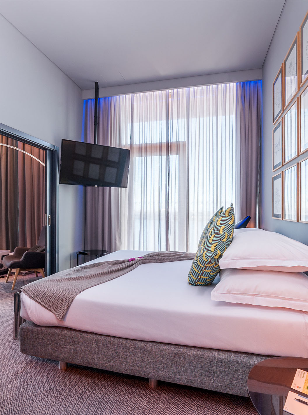 De CR7 Suite van Pestana CR7 Funchal heeft een slaapkamer met een tweepersoonsbed, een wandtelevisie en een raam