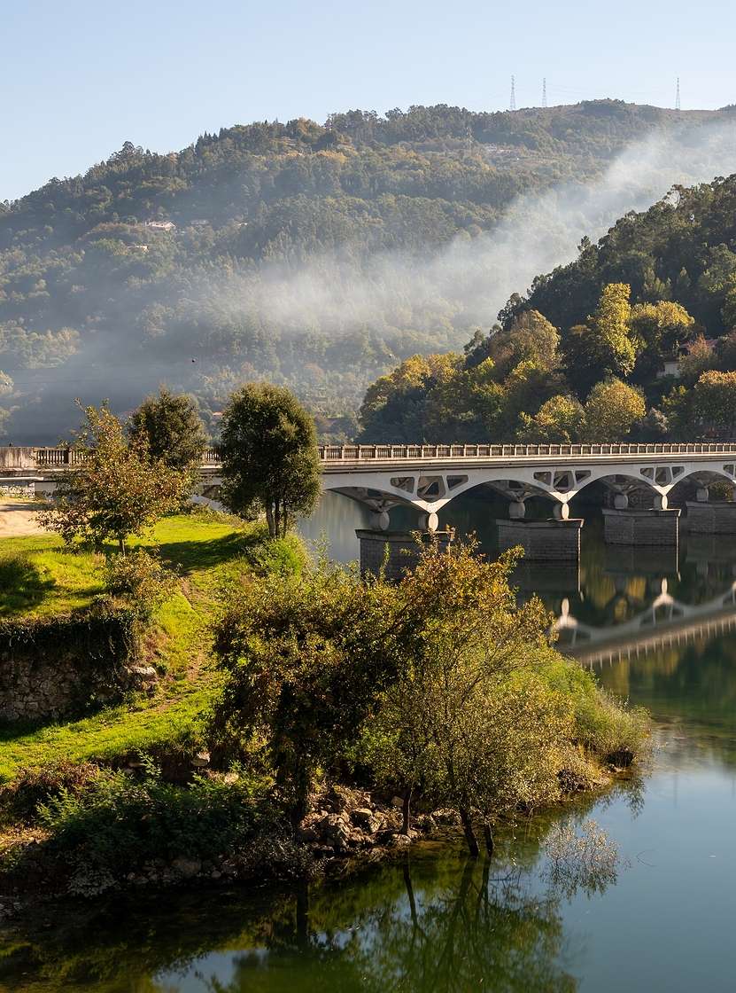 Landschap in het noorden van Portugal met een stenen brug over een rivier, omgeven door groene heuvels