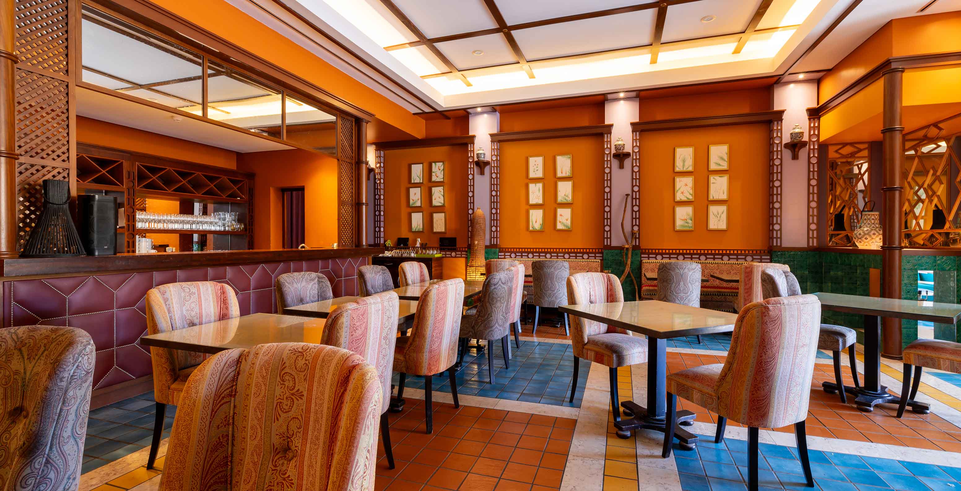 Restaurant Arab Magrebe van het 5-sterrenresort op Porto Santo heeft warme tinten, vierkante tafels en gestoffeerde stoelen.