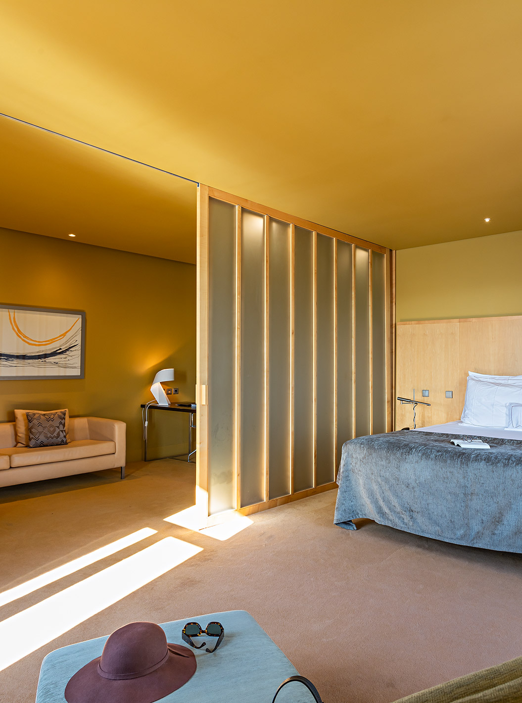 De Standard Suite heeft een groot tweepersoonsbed met een grijze deken en een bank