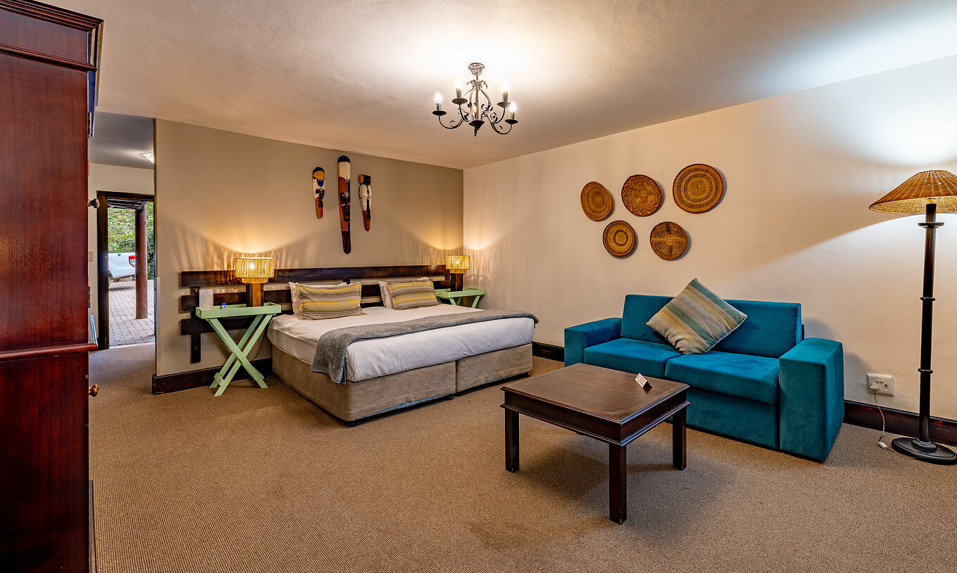 De Premium Kamer Van Pestana Kruger Lodge Heeft Een Tweepersoonsbed Een Blauwe Bank En Typisch Afrikaanse Decor