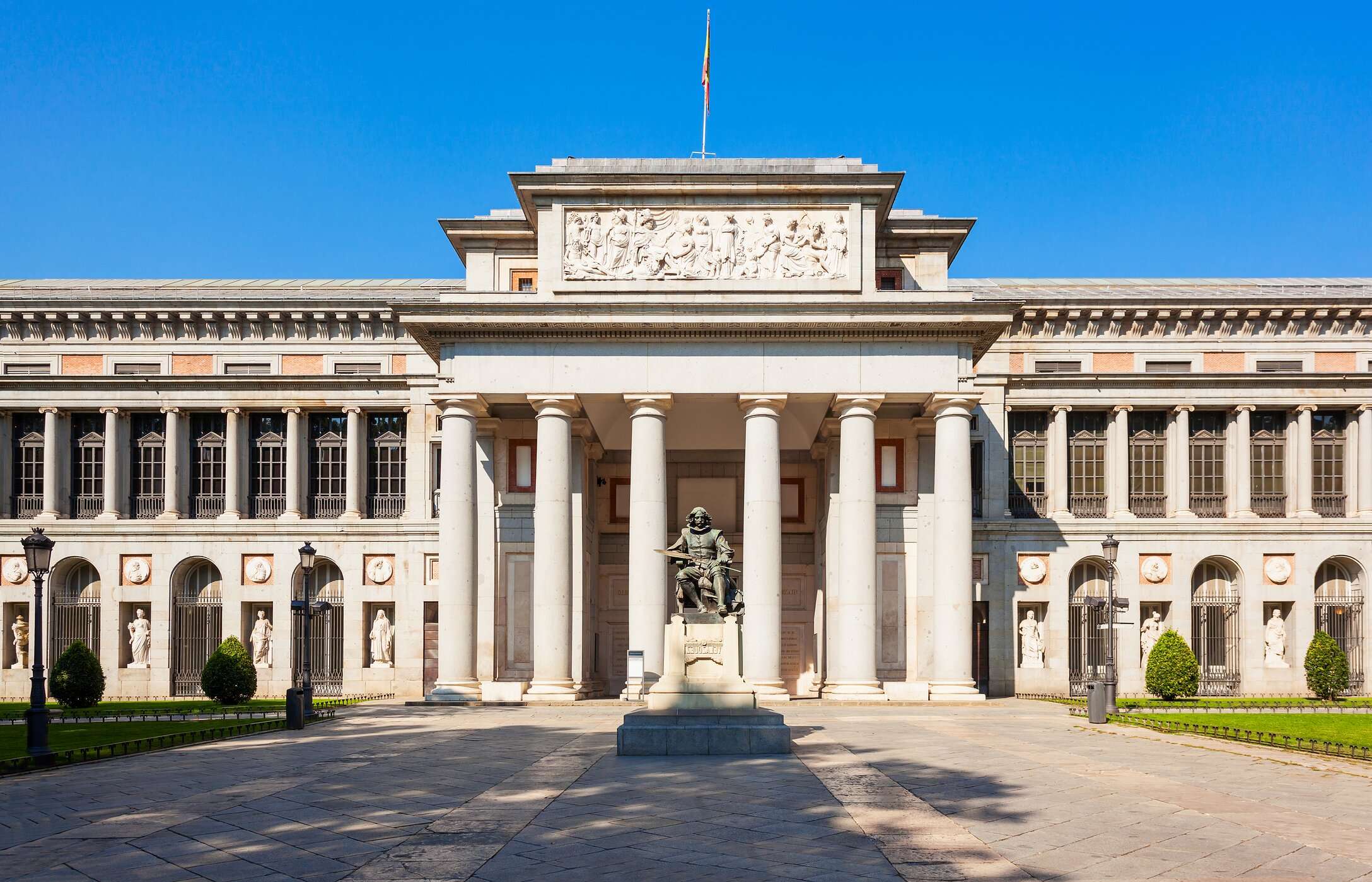 Ingang van het Prado Museum, met een standbeeld en zuilen die de trappen van het museum begeleiden
