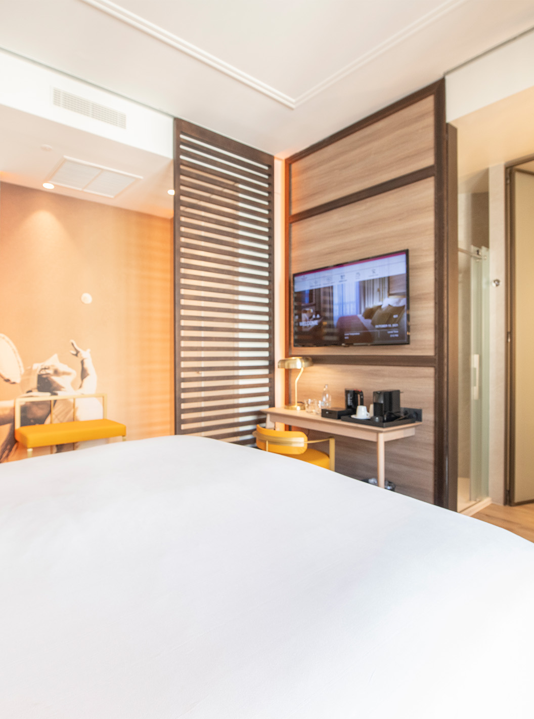 De Legend Room van Pestana CR7 Gran Vía Madrid heeft een tweepersoonsbed, stoel en lamp, twee banken en een houten scheiding