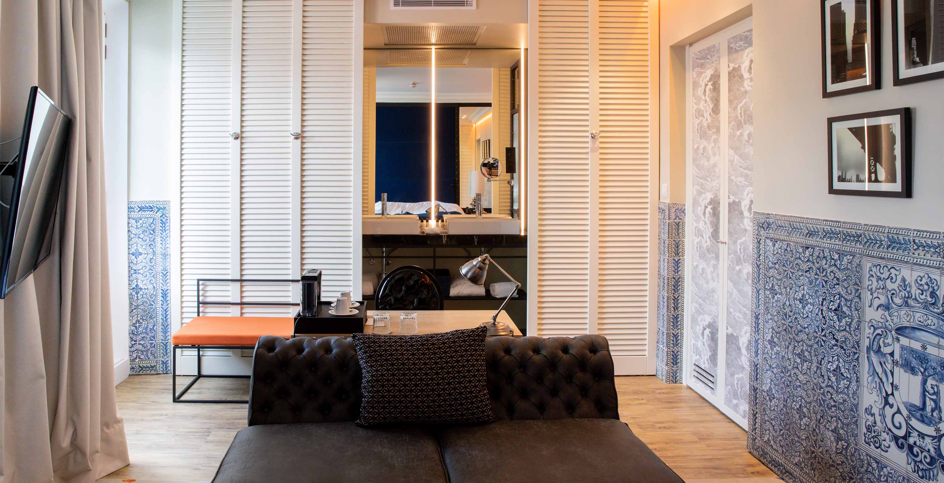 De Deluxe Plaza Mayor van Pestana Collection Plaza Mayor heeft een kamer met bank, televisie en blauwe en witte tegels op de muur