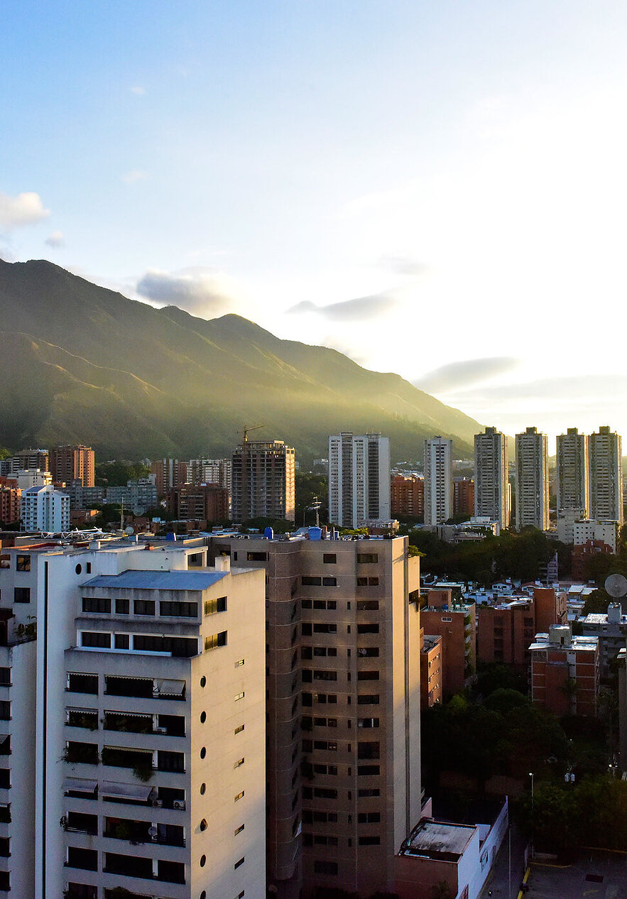 Ontdek Venezuela, een land vol natuurlijke schoonheid en levendige cultuur, met hoge gebouwen en weelderige groene bergen.