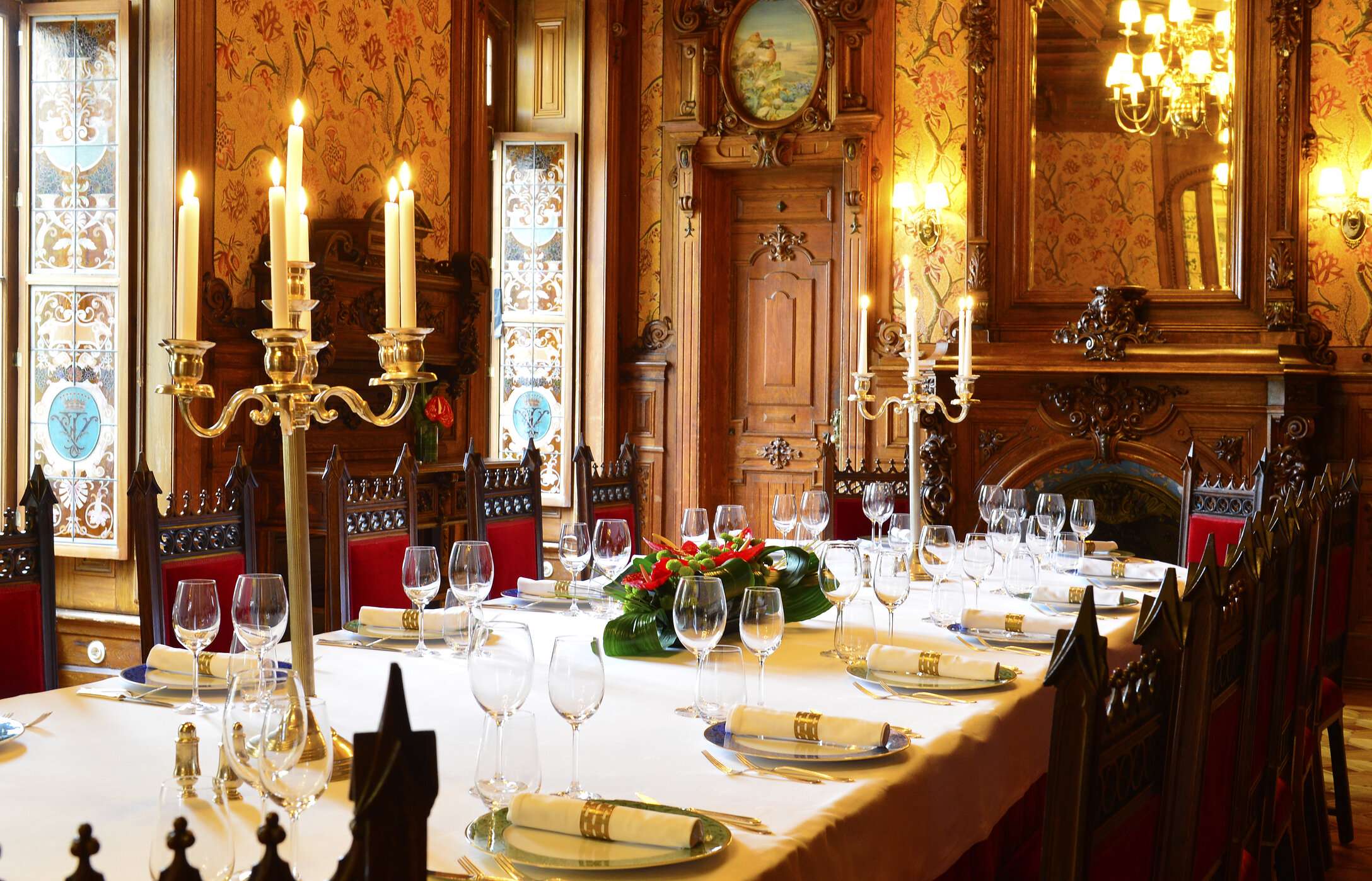 Bruiloft in een imposante zaal met elegante decoratie, lange tafel met bloemen en muren versierd met houtsnijwerk