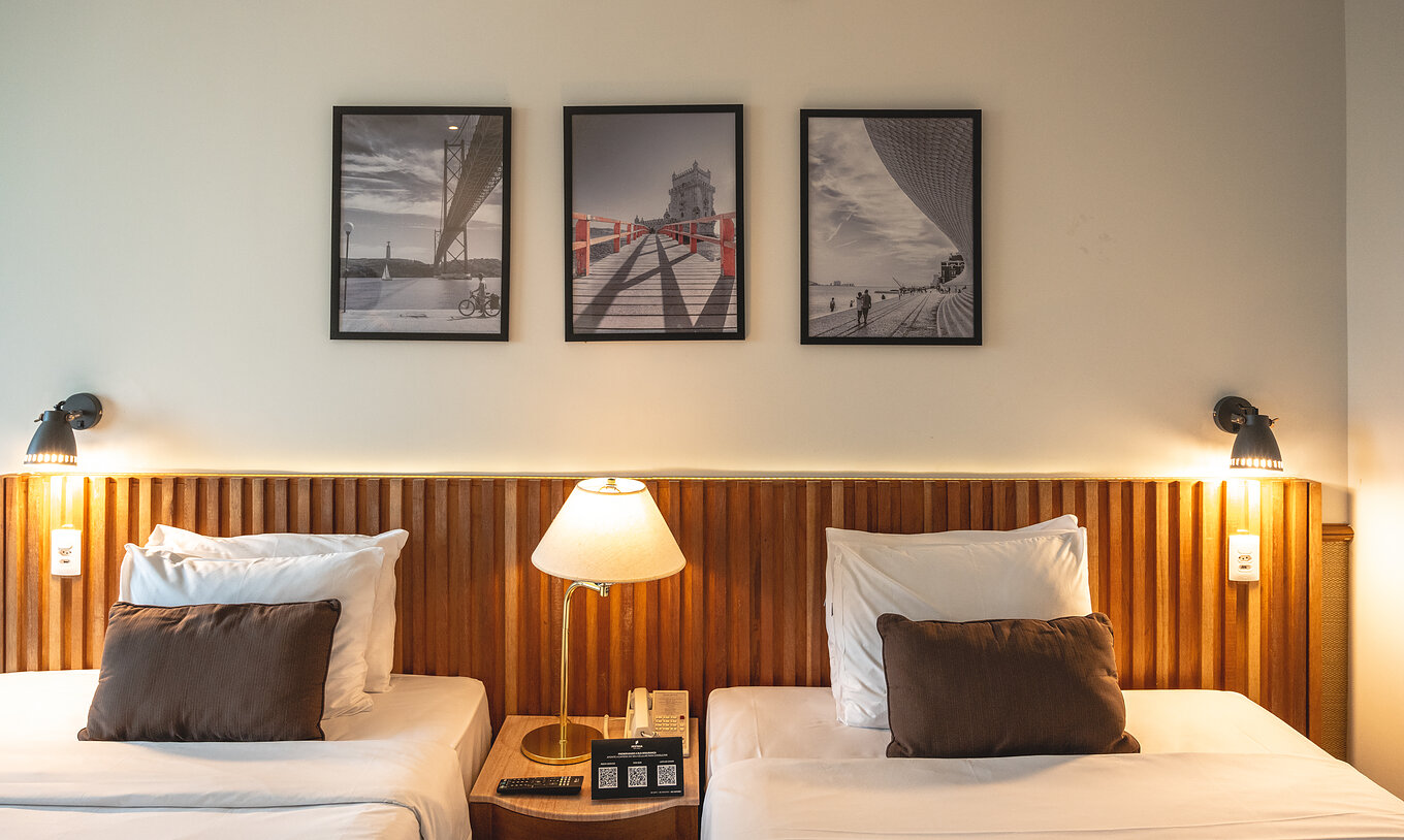 O Twin Superior do Pestana São Paulo tem duas camas individuais, uma cabeceira de cama em madeira e uma mesa no centro