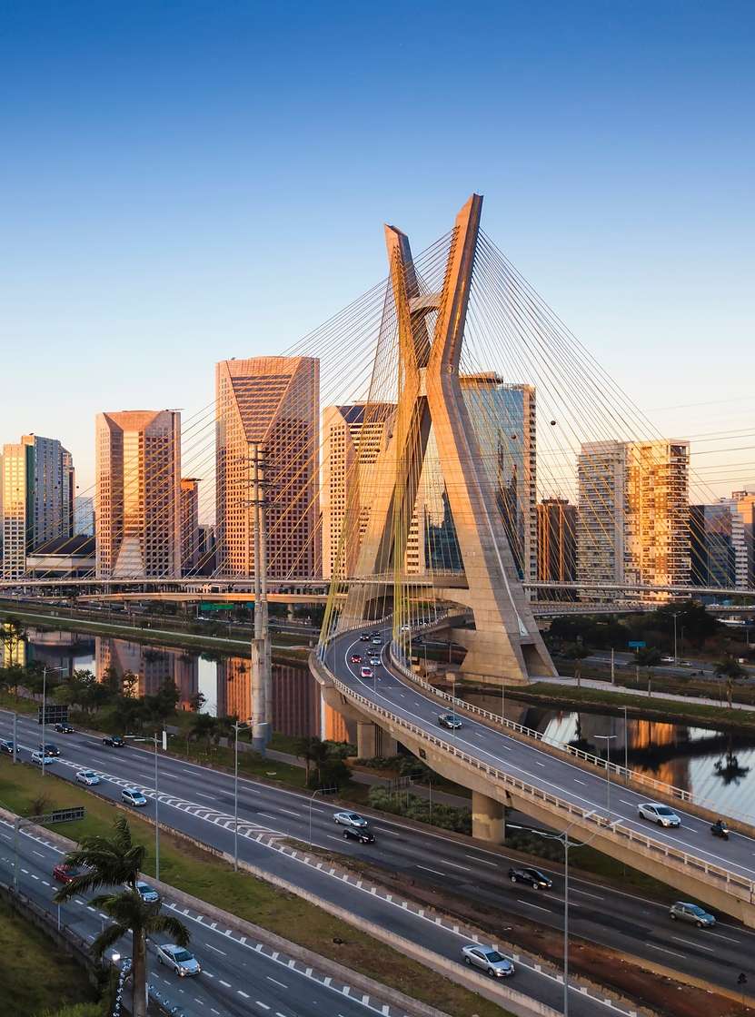 Paisagem urbana de São Paulo com a Ponte Estaida cortando o Rio Pinheiros, sob um céu azul