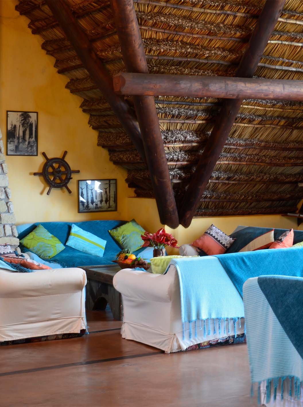 O Bungalow Suite T2 do Pestana Bazaruto Lodge tem uma sala ampla com sofás cobertos com mantas azuis e almofadas coloridas