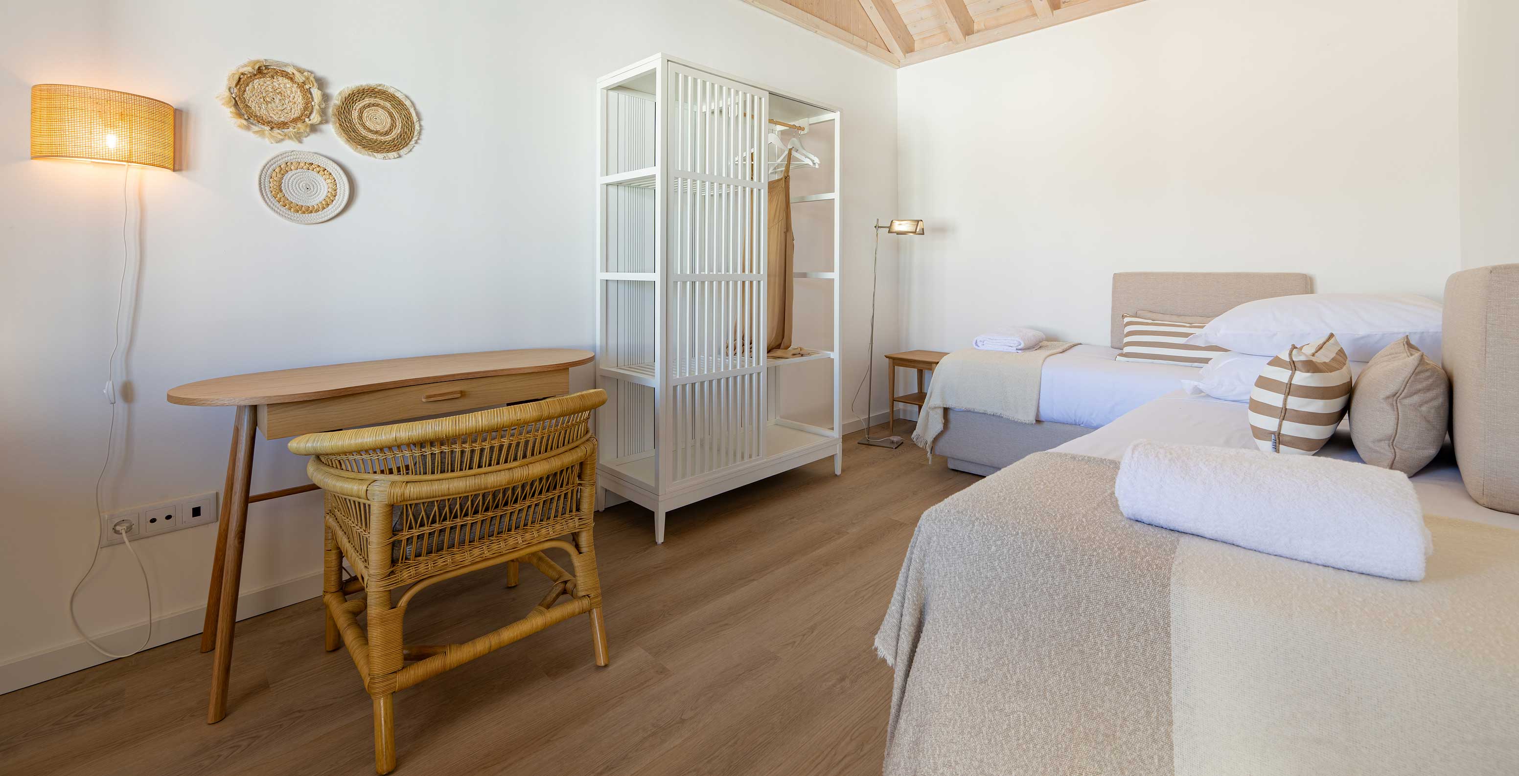 A Premium Villa do Pestana Comporta Village Residences tem um quarto com cama, uma mesa e uma cadeira de vime