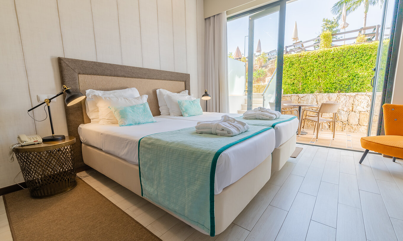 A Suite Garden do Pestana Alvor Park tem duas camas, cadeirão, cortinados e varanda com mesa e cadeiras