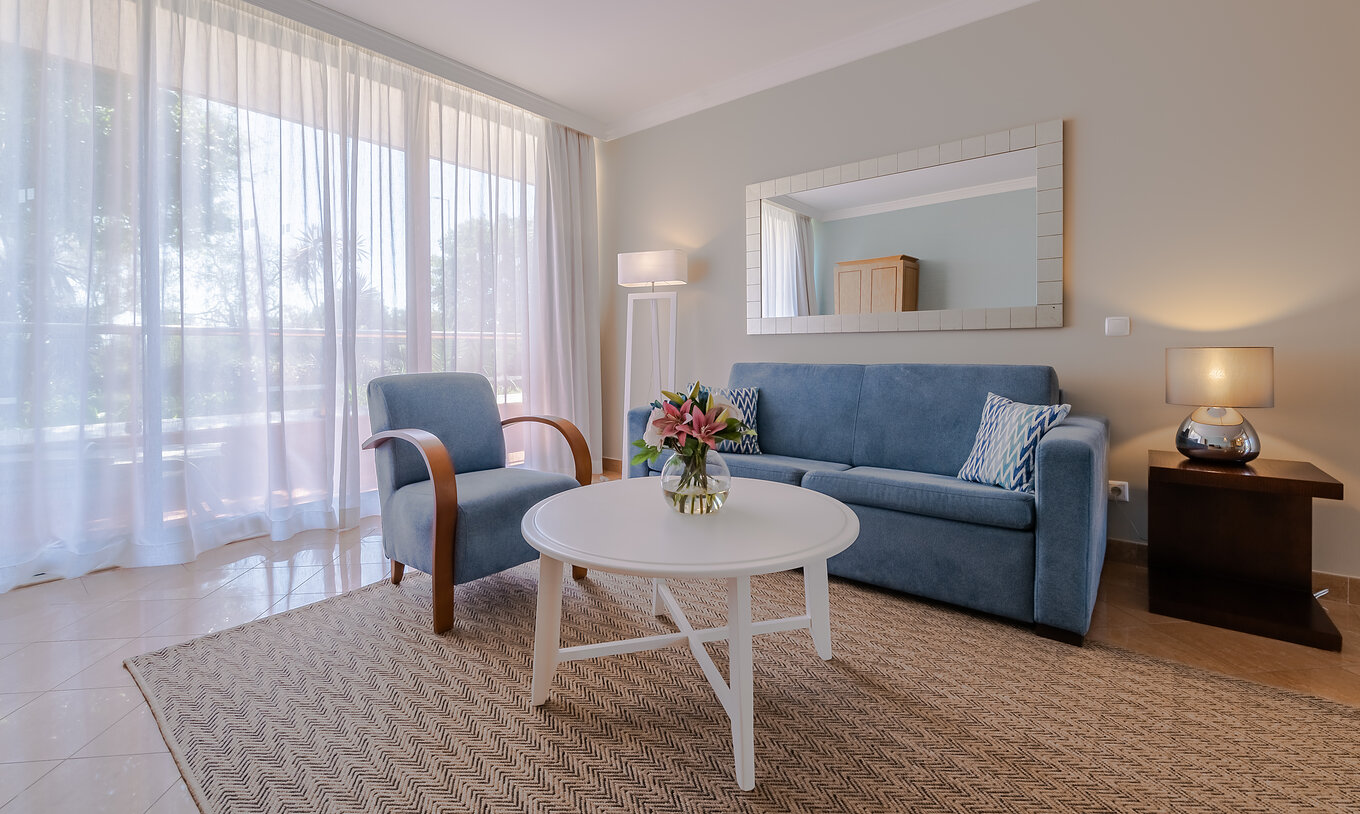 O T1 - com 1 Quarto do Pestana Alvor Park tem uma sala de estar com um sofá e um cadeirão azuis