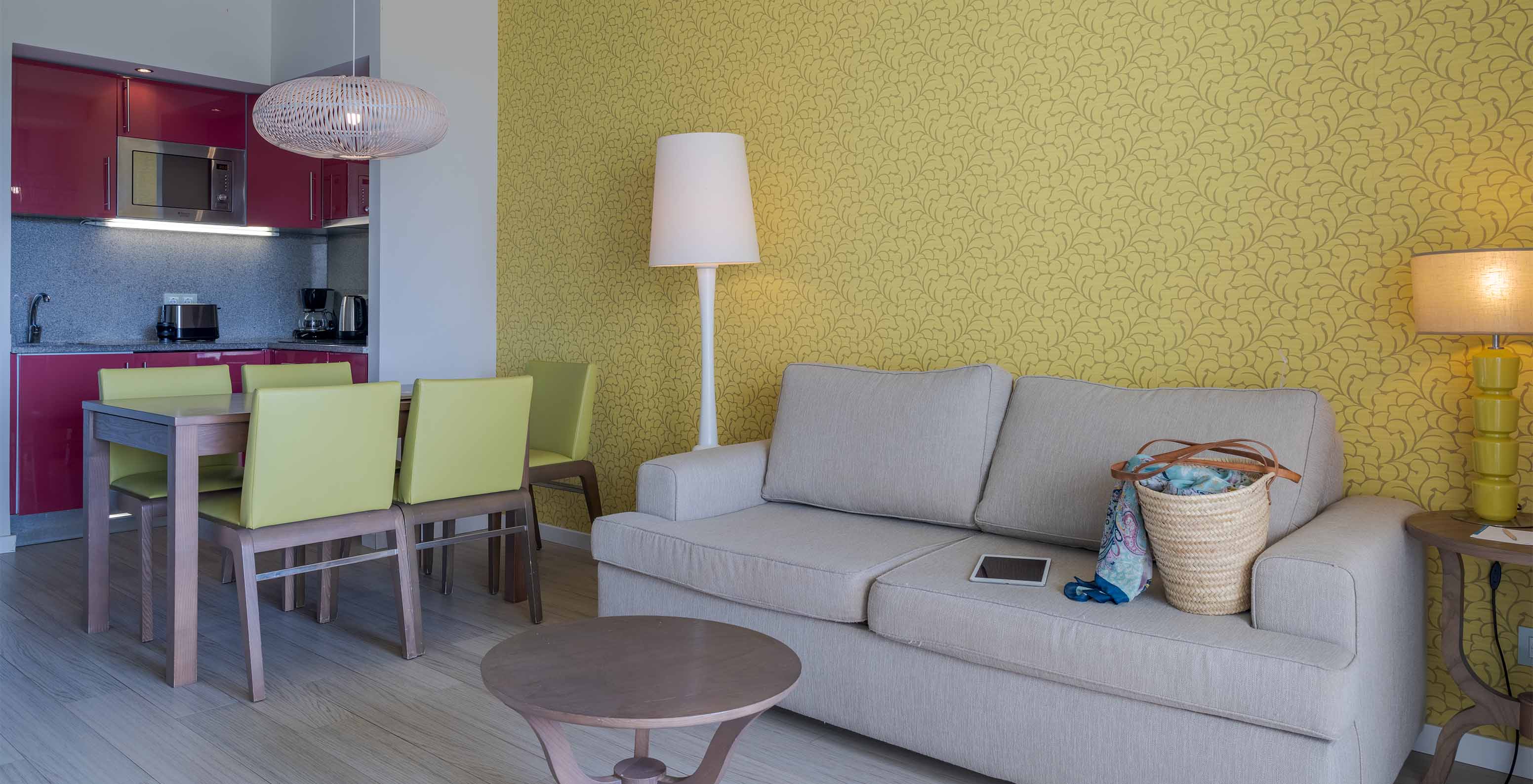 A Suite T1 Vista Jardim do Pestana Alvor Praia tem uma mesa de jantar com cinco cadeiras verdes e um sofá com mesa de apoio