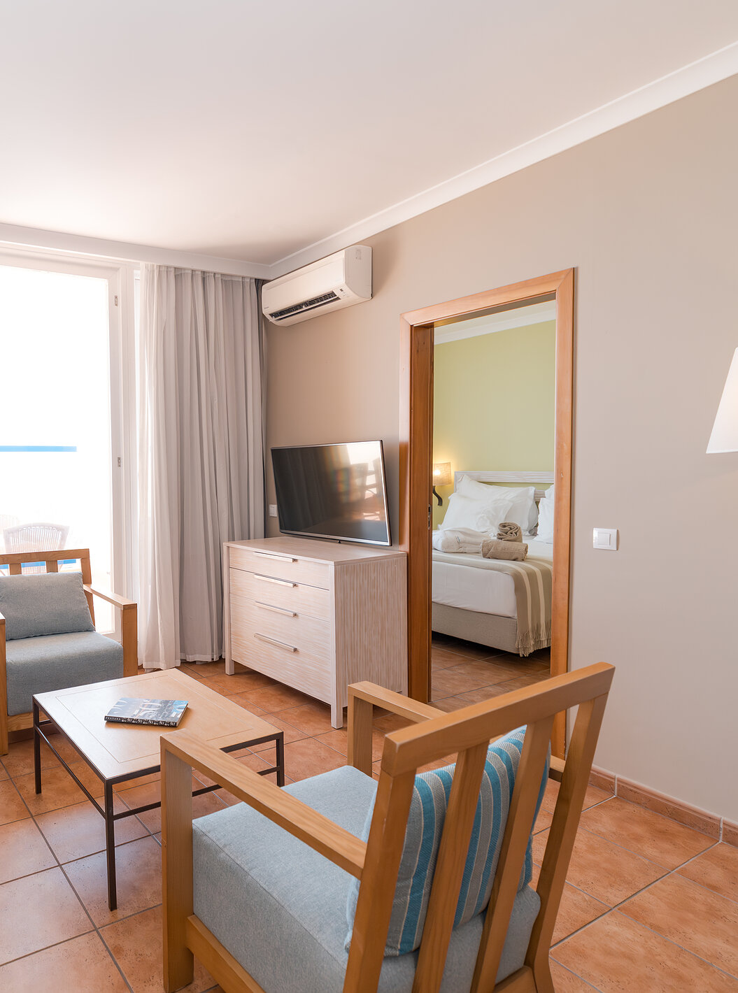 A Suite Superior Vista Mar do Pestana Viking tem uma sala com sofá, poltronas, televisão, ar condicionado e acesso à varanda