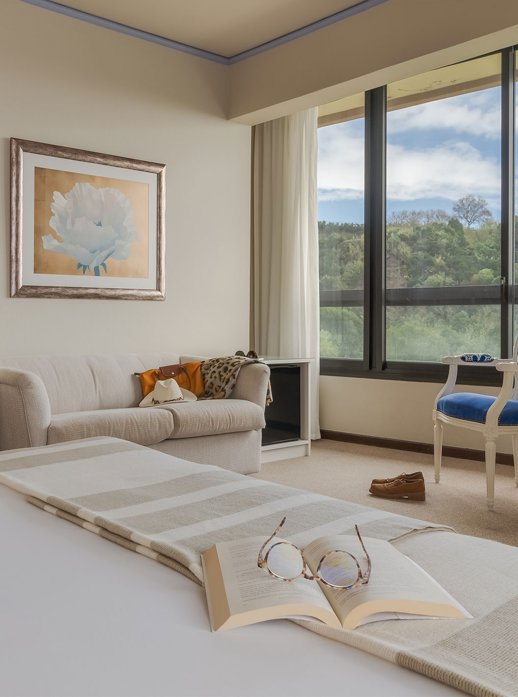 O Standard Vista Mar do Pestana Bahia Praia tem uma scretária, um sofá e uma cadeira perto da janela, com vista para o jardim