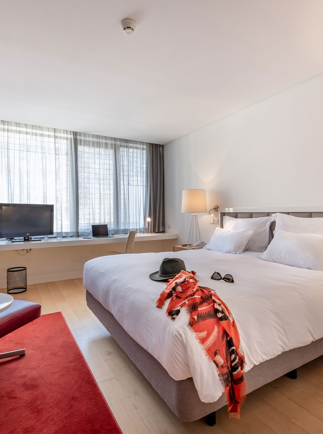 O Quarto Clássico do Pestana Cidadela Cascais tem uma cama de casal, uma televisão, um tapete vermelho e uma janela grande