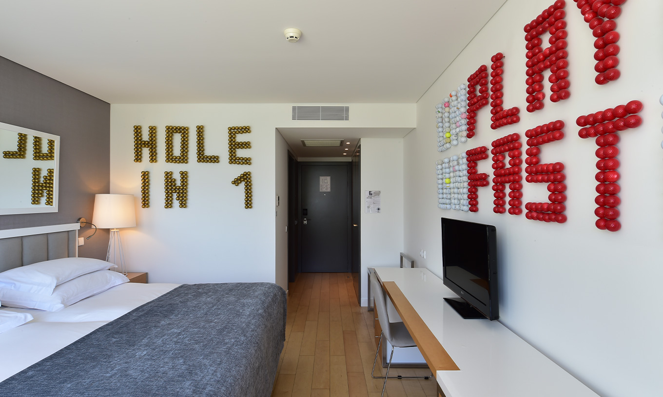 O Quarto Superior com Varanda do Pestana Cidadela Cascais tem um corredor na entrada, uma televisão e arte em duas paredes