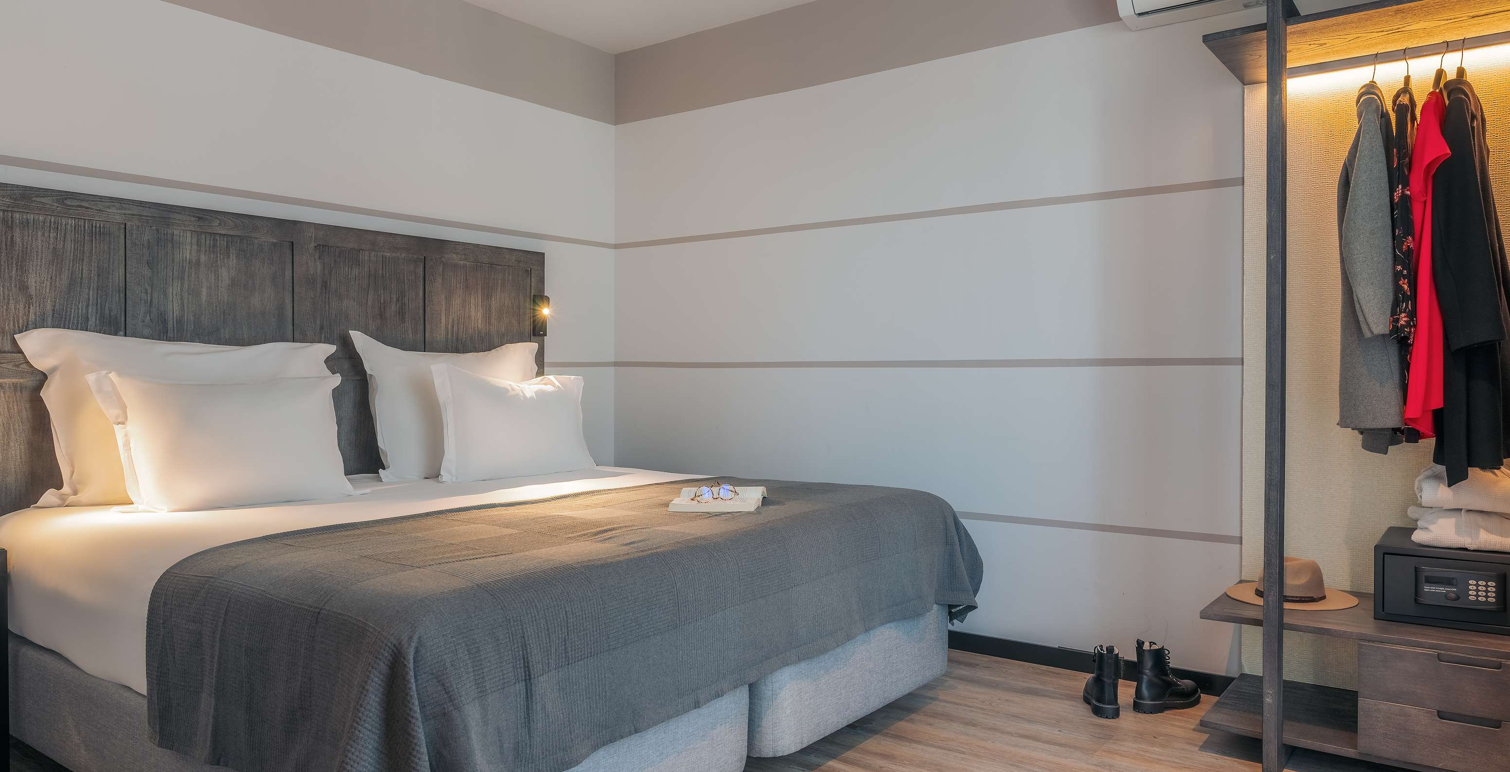 A Rooftop Junior Suite do Pestana Lisboa Vintage tem uma cama de casal, umas botas no chão de madeira e um armário com roupa
