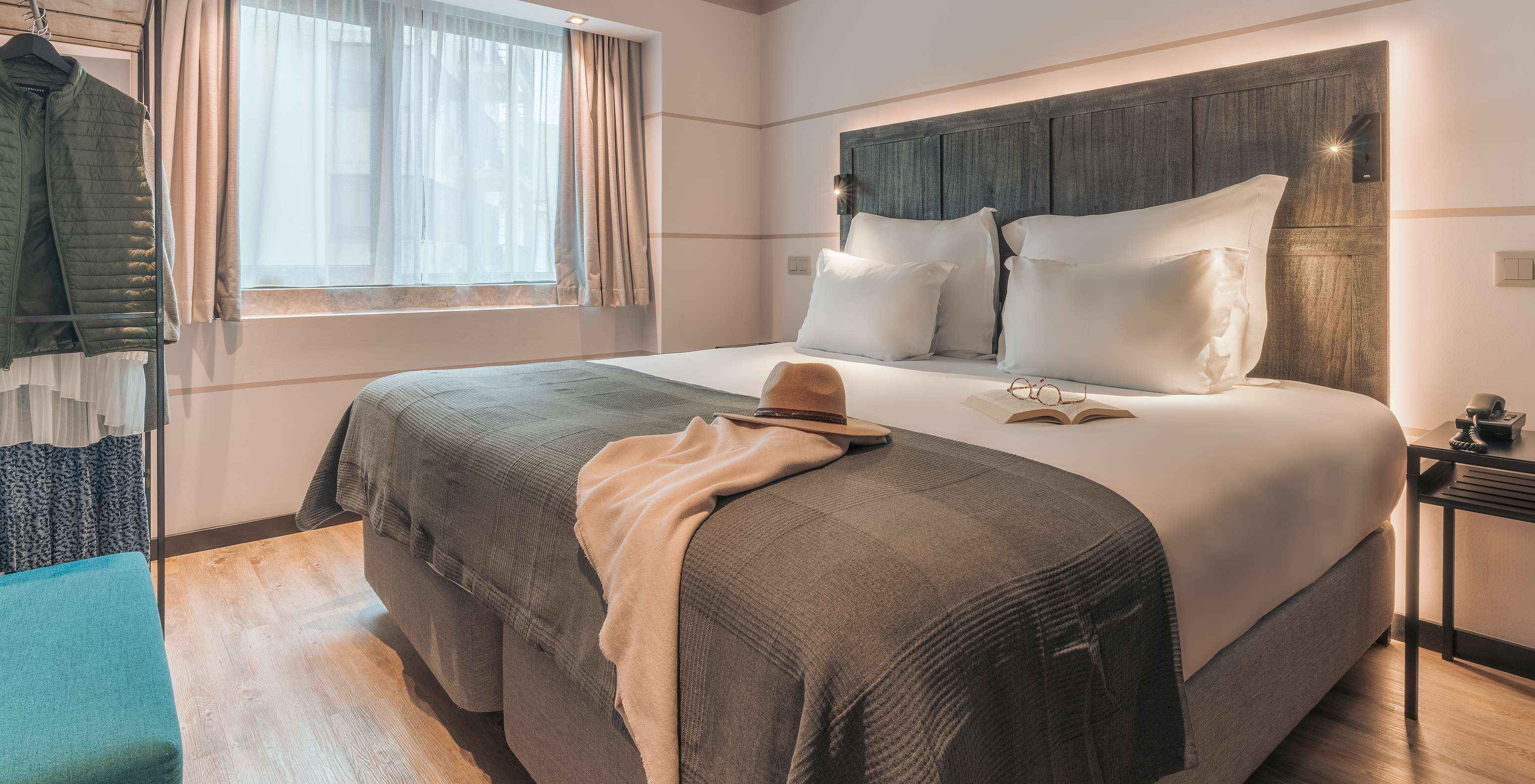 A Junior Suite do Pestana Lisboa Vintage tem uma cama de casal com uma manta, um sofá azul, mesa de cabeceira e um armário 