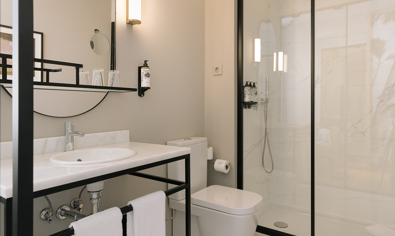 O Premium Corner do Pestana Rua Augusta Lisboa tem uma casa de banho com lavatório com espelho, toalhas, sanita e duche
