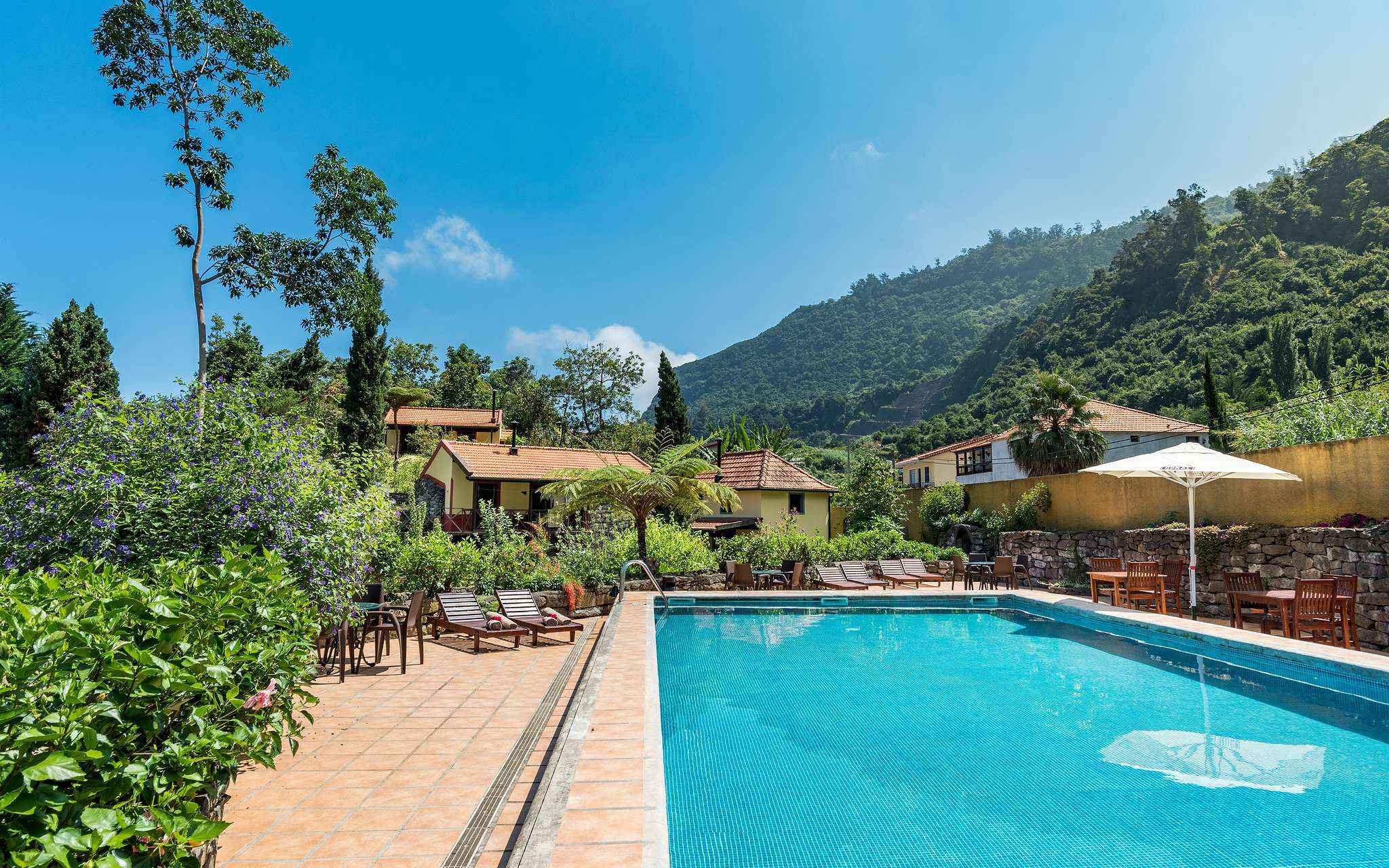 Piscina do Pestana Quinta do Arco, Hotel de Turismo Rural na Madeira, com espreguiçadeiras, vegetação, villas e montanhas