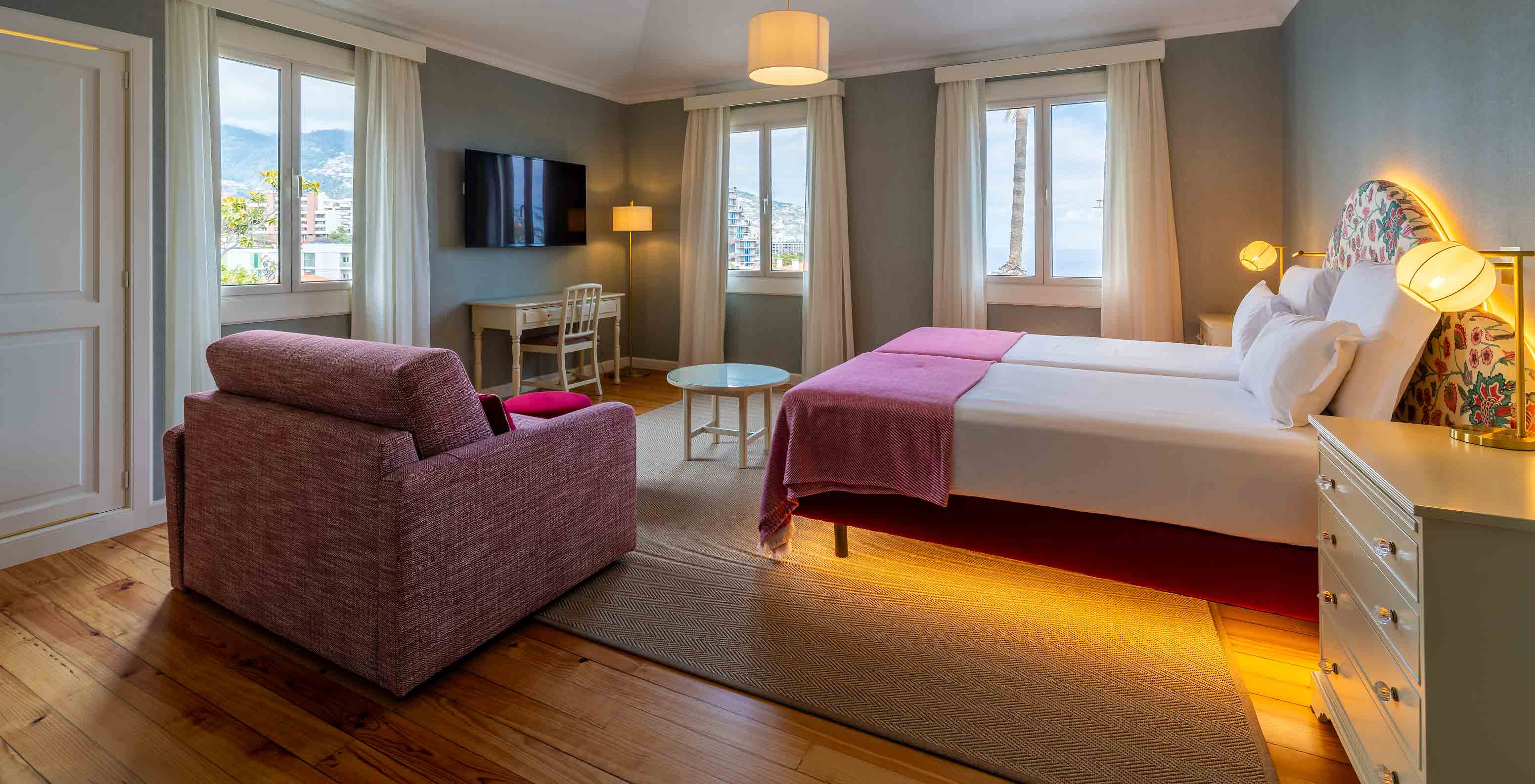 O Quarto Junior Suite Vista Mar Parcial do Pestana Quinta Perestrello tem uma cama de casal, um sofá e televisão