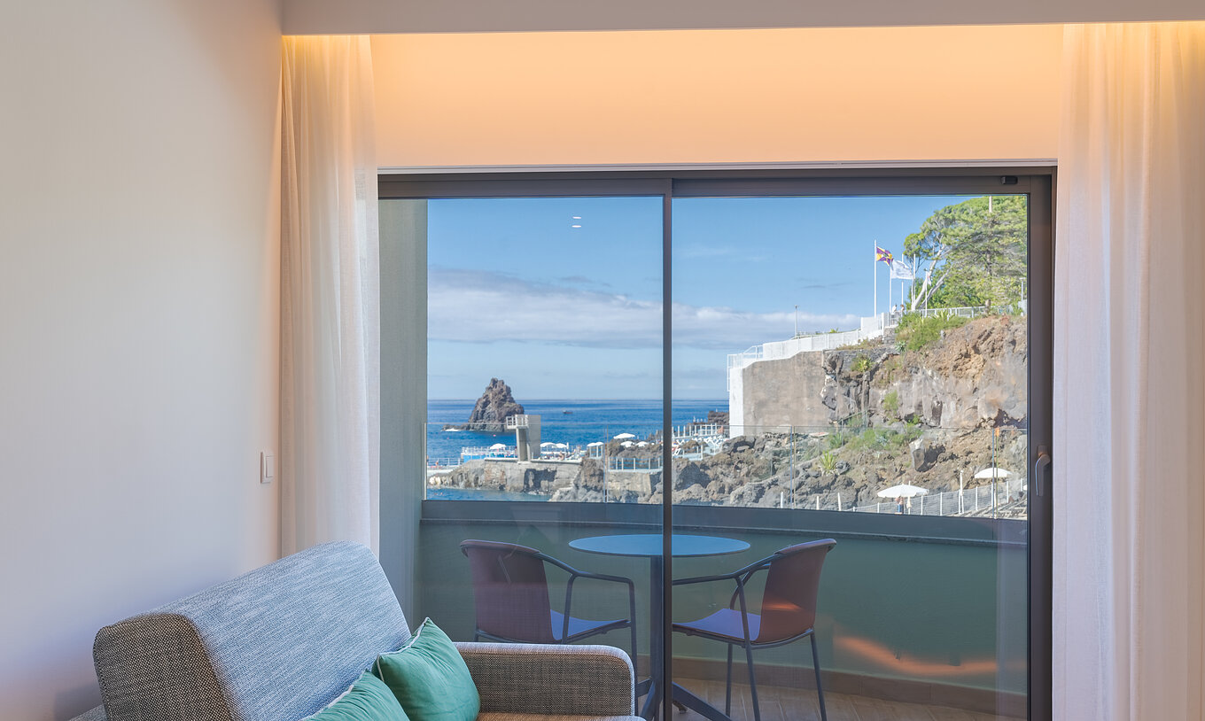 O Clássico Vista Mar Lateral do Pestana Vila Lido Madeira tem um sofá ao lado da varanda com vista lateral para o mar