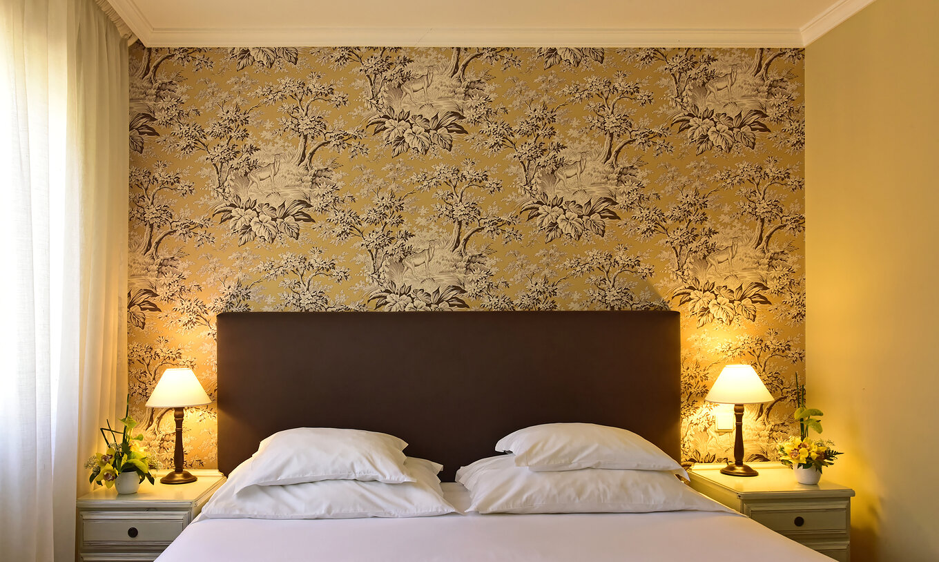 O Twin superior com Jacuzzi do Pestana Village tem uma cama de casal com cabeceira e colcha castanhas, e papel de parede