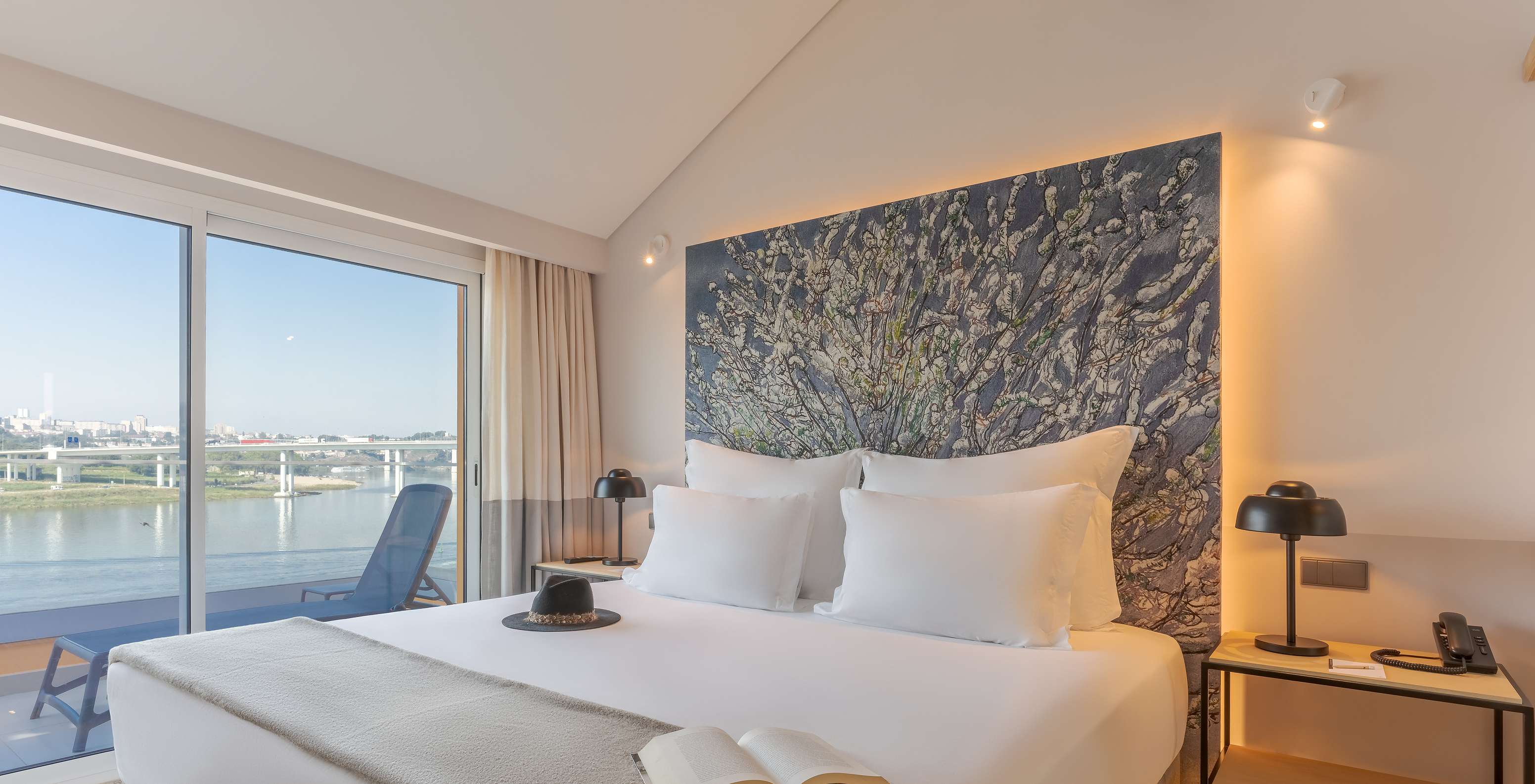 A Suite Douro do Pestana Douro Riverside conta com uma cama de casal com mesa de cabeceira e varanda com vista para o rio