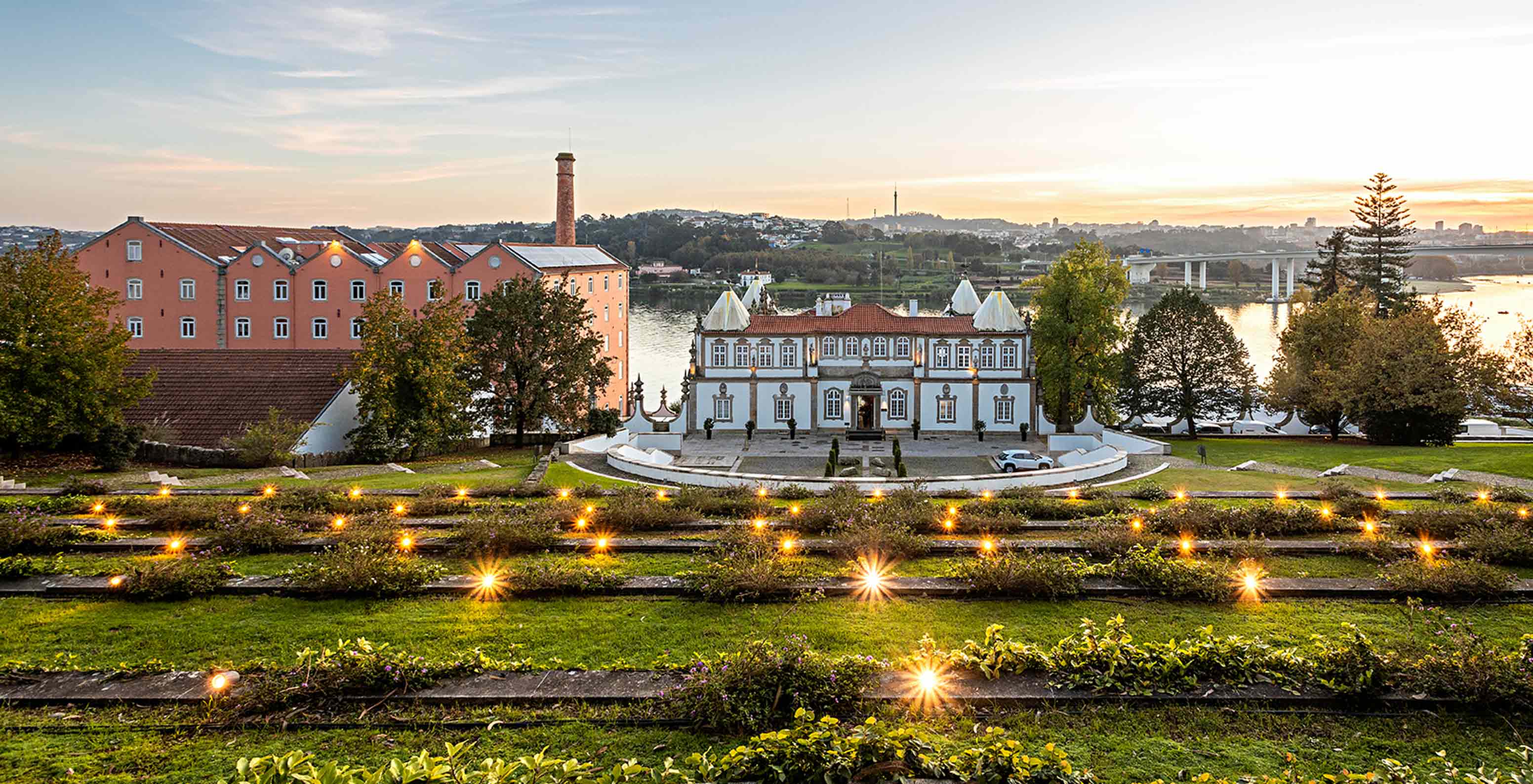 Vista exterior da fachada do Pestana Palácio do Freixo, rodeado de jardins e com vista para o rio Douro ao pôr do sol