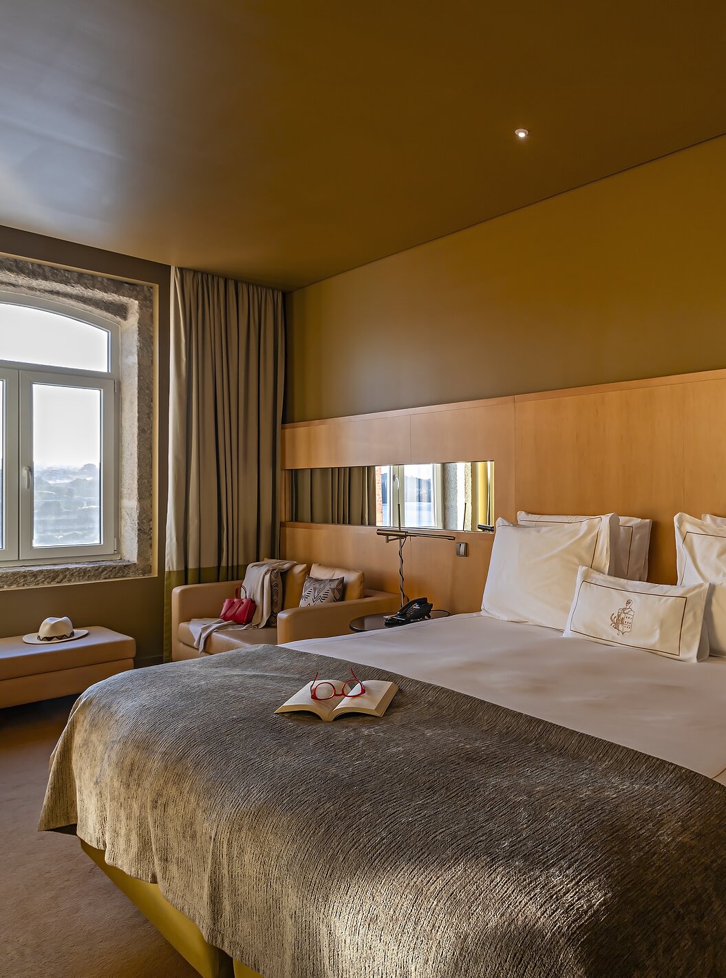 O Executive Superior do Pestana Palácio do Freixo tem uma cama de casal, um sofá e um puff ao lado da janela