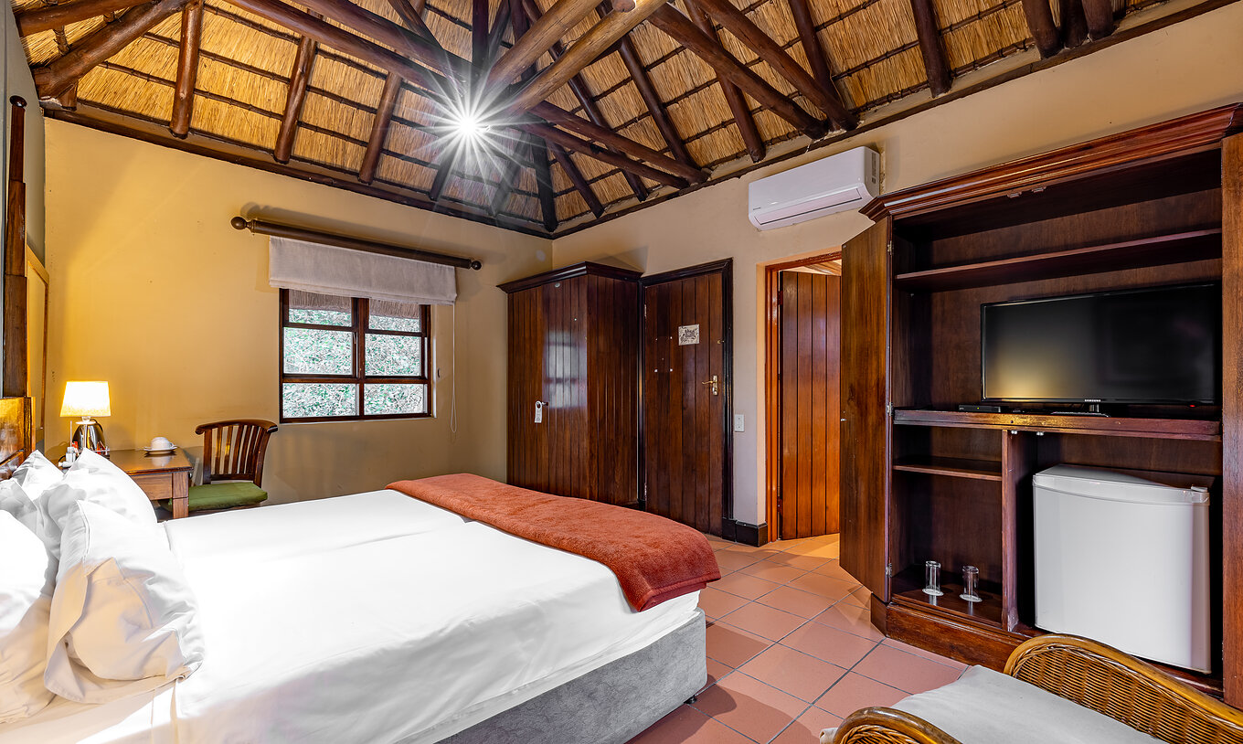 O Quarto Standard do Pestana Kruger Lodge tem duas camas individuais, ar condicionado, televisão e decoração em madeira