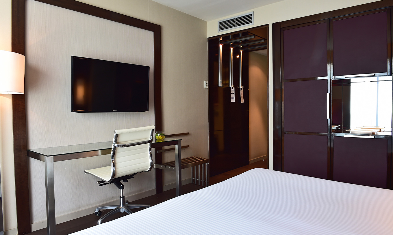 O Quarto Premium do Pestana Arena Barcelona tem uma televisão no fundo da cama e um armário em tom roxo para arrumação