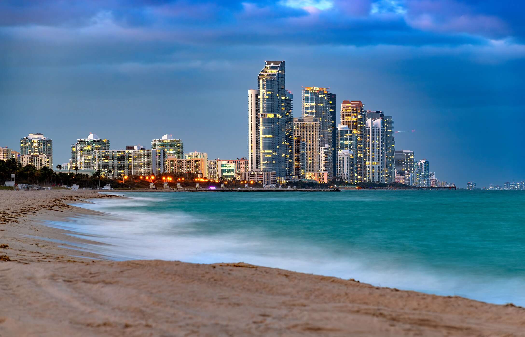 Praia de Sunny Isles em Miami com águas cristalinas, areia branca e prédios modernos ao fundo