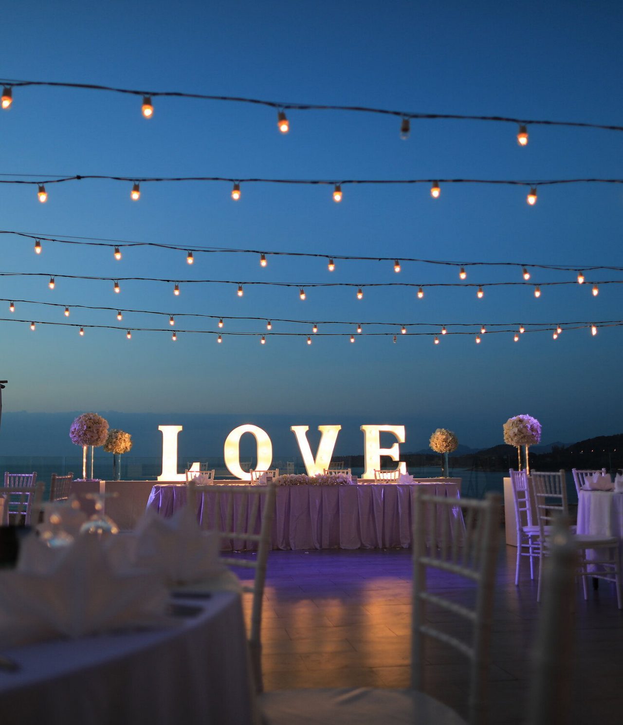 Dekoration für Ihre besondere Gelegenheit, mit Außentischen, hängenden Lichtern und einem großen Schild "Love"